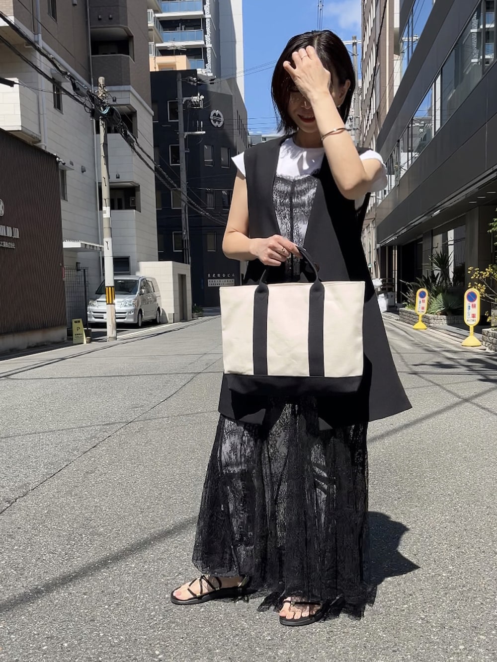 ブラック系のワンピース、ブラック系のサンダル、ブラック系のベストを着用したレディースの夏コーディネートの3枚目の写真