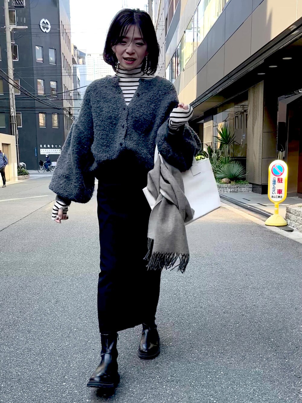 ホワイト系のトートバッグ、グレー系のカーディガン/ボレロ、ブラック系のスカートを着用したレディースの秋コーディネートの2枚目の写真