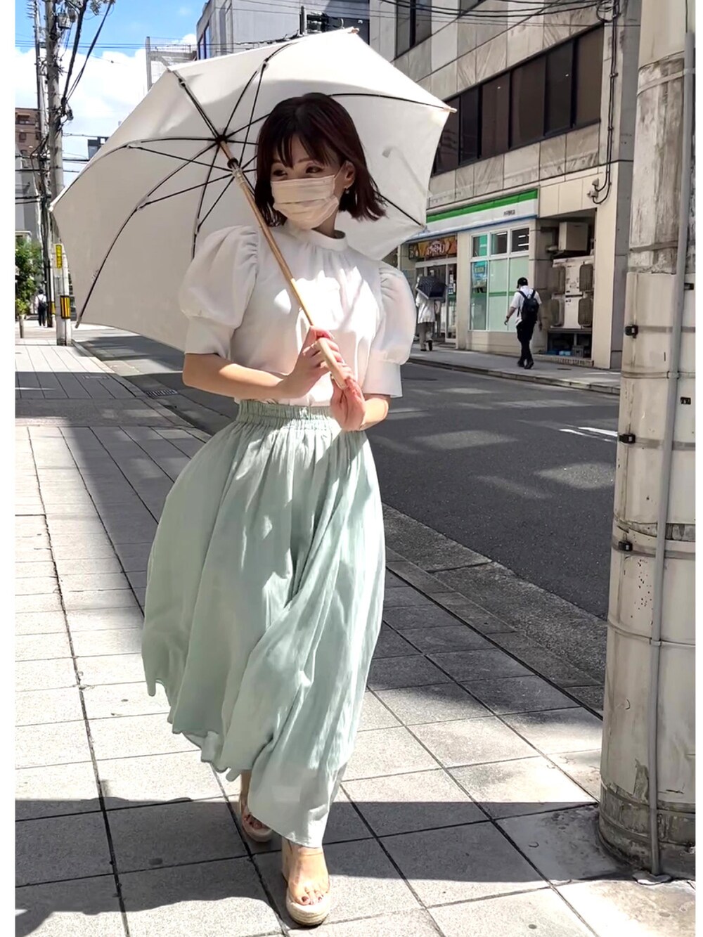 ホワイト系のシャツ/ブラウス、グリーン系のスカート、ベージュ系のサンダルを着用したレディースの夏コーディネートの2枚目の写真