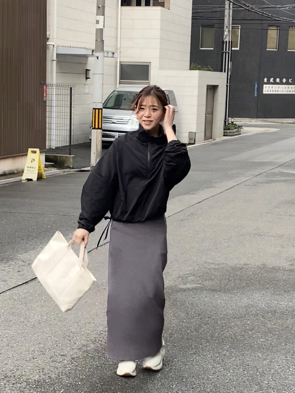 ブラック系のナイロンジャケット、グレー系のスカート、ホワイト系のトートバッグを着用したレディースの春コーディネートの4枚目の写真