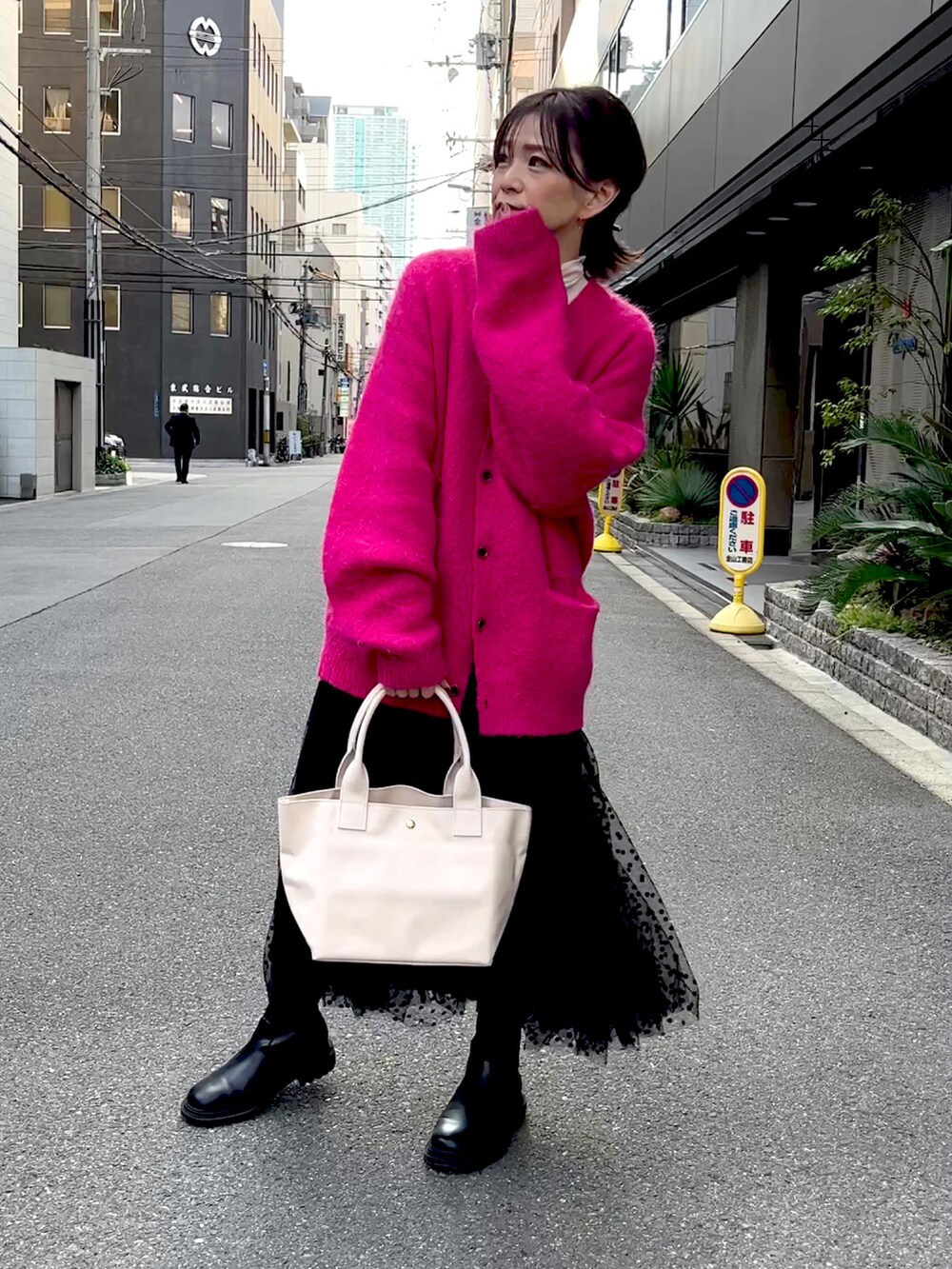 ホワイト系のトートバッグ、ピンク系のカーディガン/ボレロ、ブラック系のスカートを着用したレディースの秋コーディネートの3枚目の写真