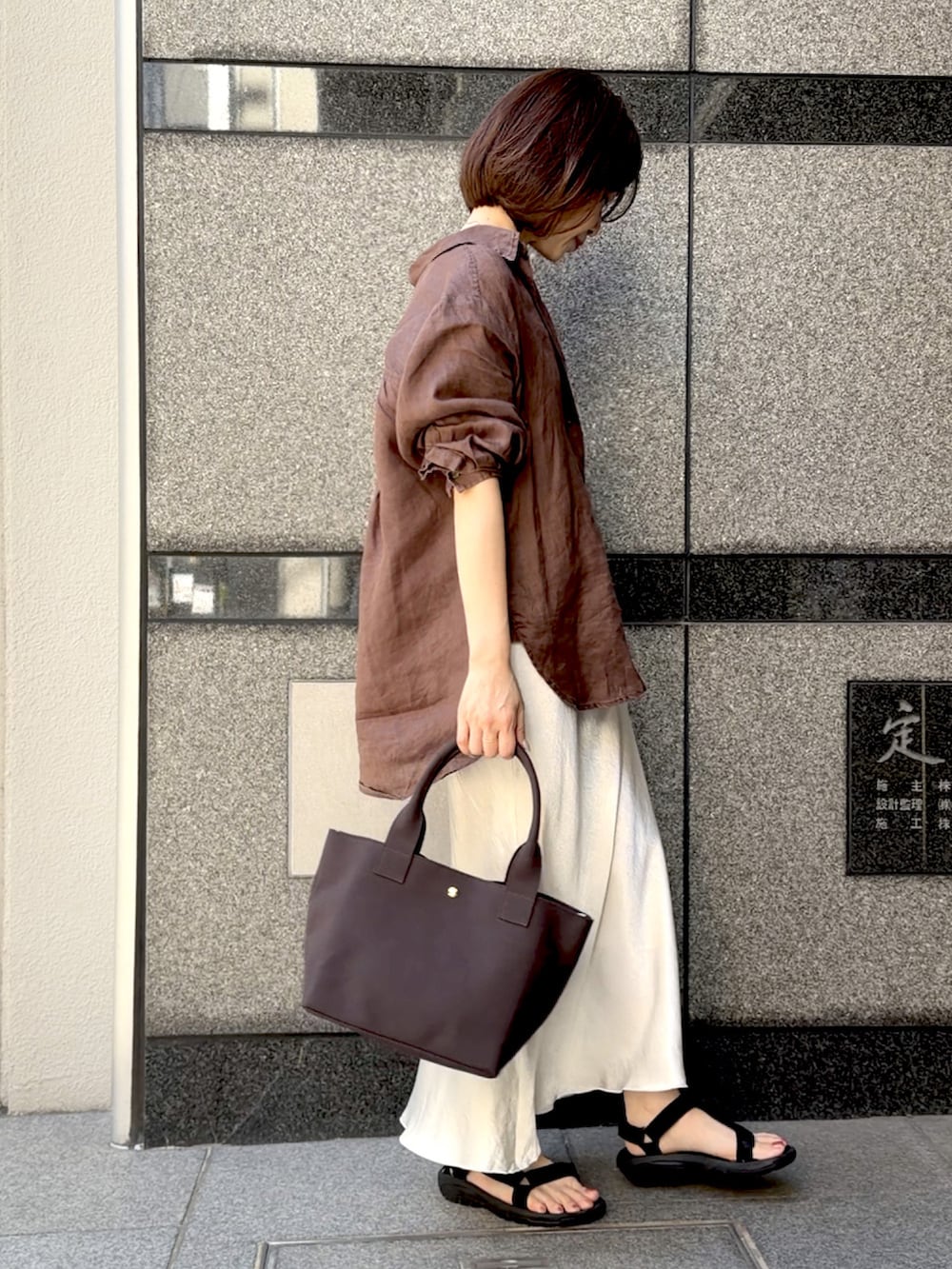 グレー系のトートバッグ、ブラウン系のシャツ/ブラウス、ブラック系のサンダルを着用したレディースの春コーディネートの5枚目の写真