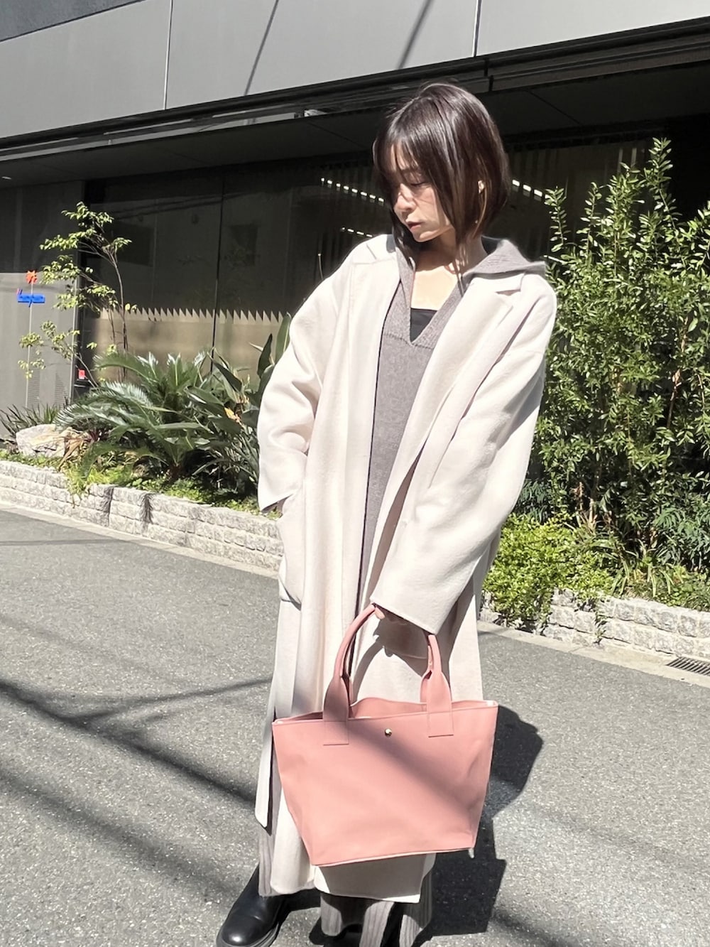 ピンク系のトートバッグ、ホワイト系のチェスターコート、グレー系のワンピースを着用したレディースの冬コーディネートの2枚目の写真
