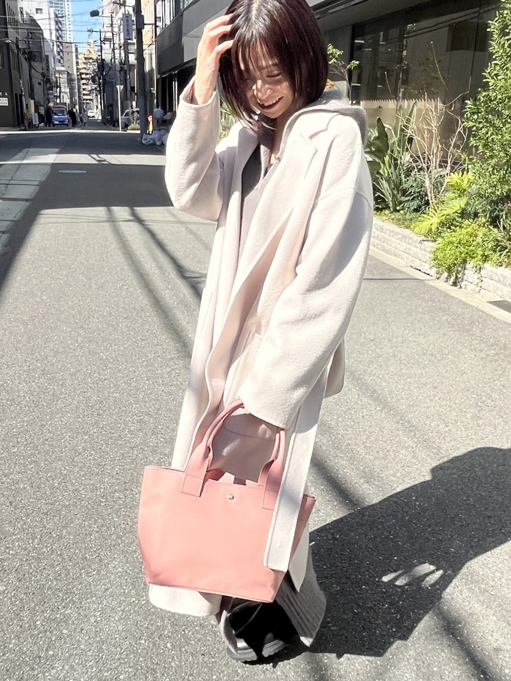ピンク系のトートバッグ、ホワイト系のチェスターコート、グレー系のワンピースを着用したレディースの冬コーディネートの3枚目の写真