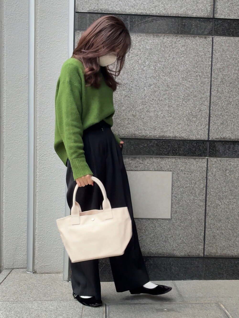 ホワイト系のトートバッグ、グリーン系のニット/セーター、ブラック系のスラックスを着用したレディースの冬コーディネートの3枚目の写真