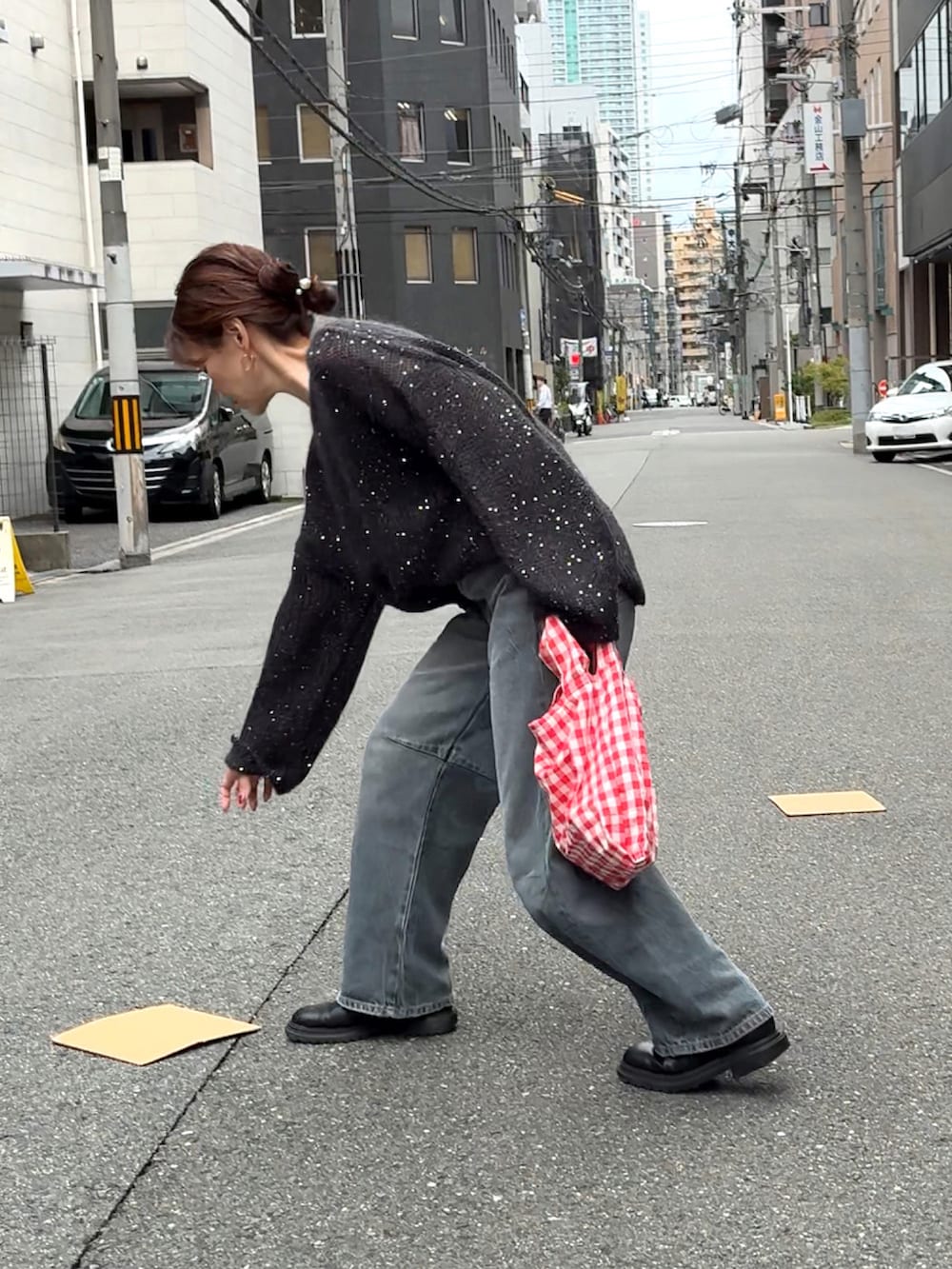 ブラック系のニット/セーター、ブルー系のデニムパンツ、レッド系のエコバッグ/サブバッグを着用したレディースの秋コーディネートの5枚目の写真