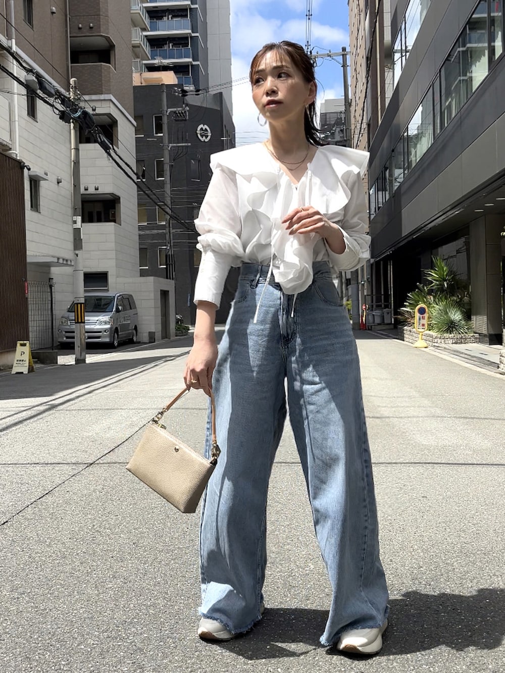 グレー系のショルダーバッグ、ホワイト系のシャツ/ブラウス、グレー系のデニムパンツを着用したレディースの春コーディネートの3枚目の写真