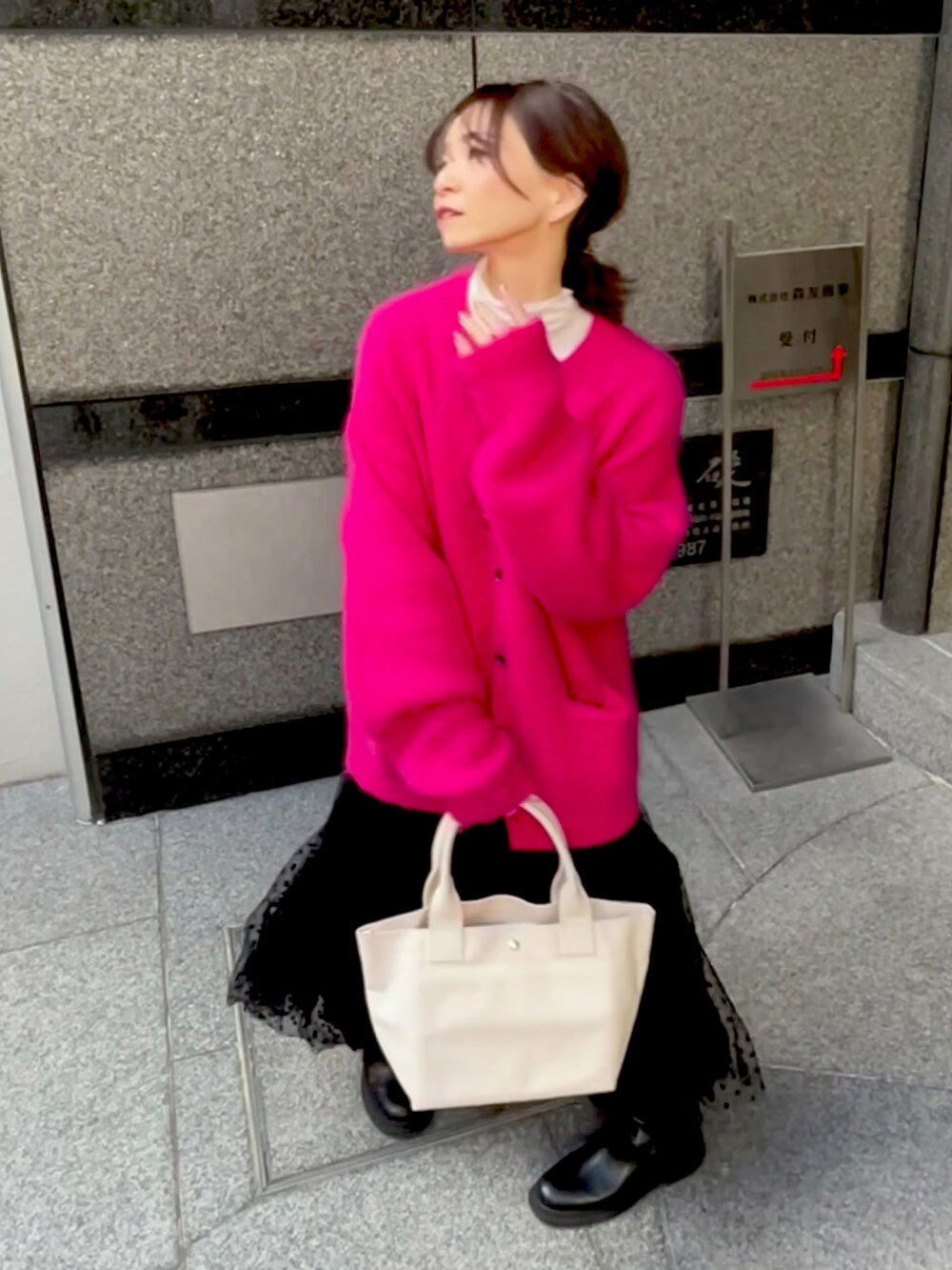 ホワイト系のトートバッグ、ピンク系のカーディガン/ボレロ、ブラック系のスカートを着用したレディースの秋コーディネートの2枚目の写真