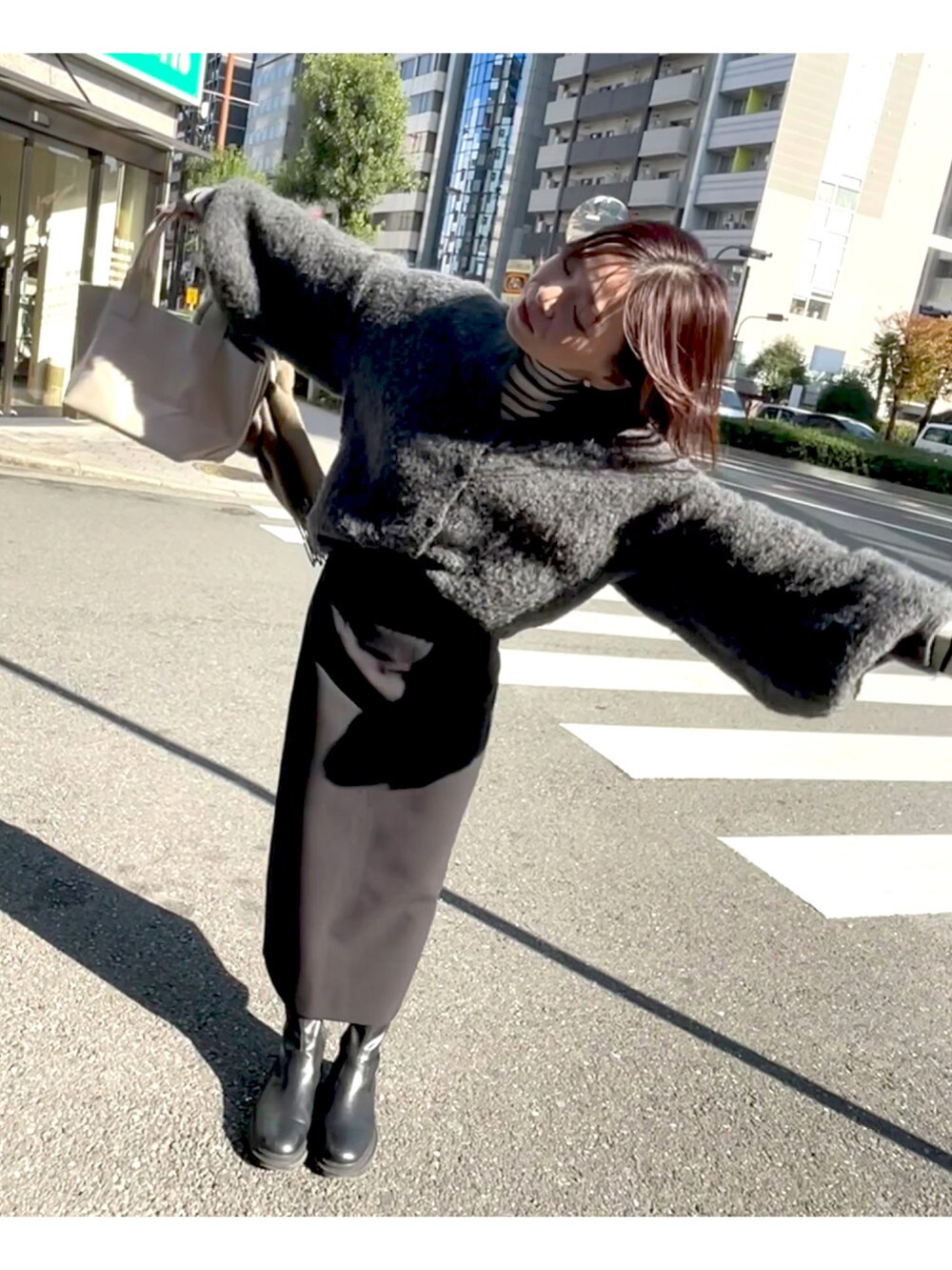 ホワイト系のトートバッグ、グレー系のカーディガン/ボレロ、ブラック系のスカートを着用したレディースの秋コーディネートの5枚目の写真