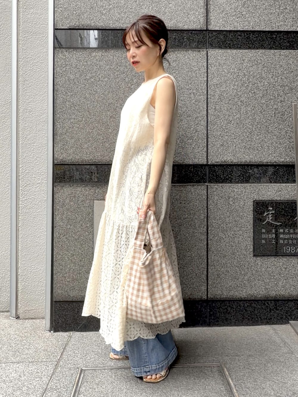 ベージュ系のワンピース、ベージュ系のエコバッグ/サブバッグ、ブルー系のデニムパンツを着用したレディースの夏コーディネートの4枚目の写真