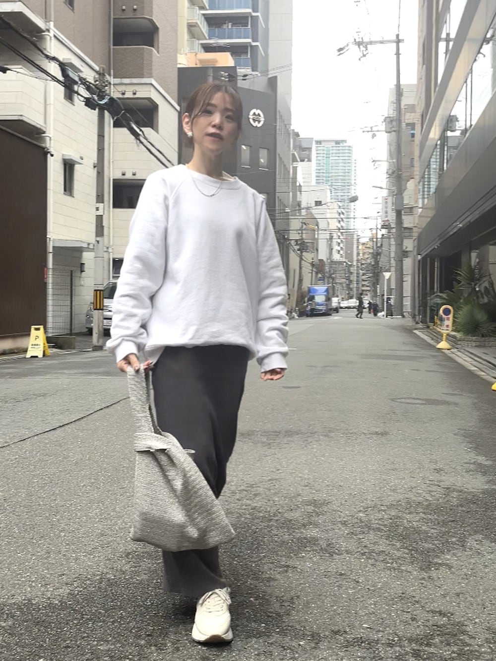 シルバー系のハンドバッグ、グレー系のスカート、ホワイト系のスニーカーを着用したレディースの春コーディネートの3枚目の写真