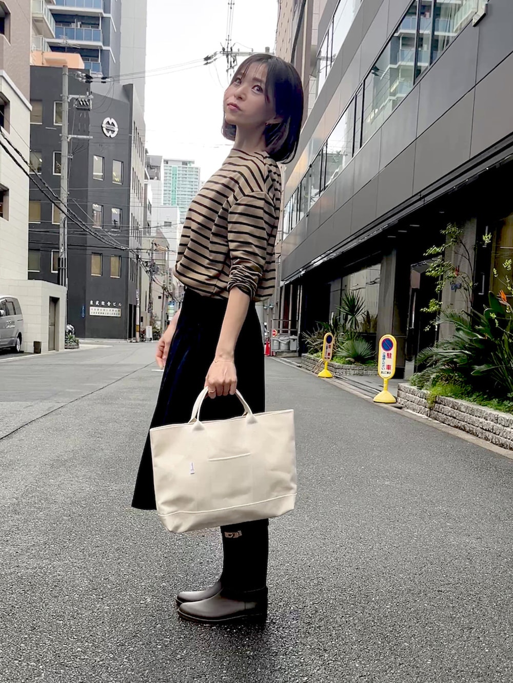ブラック系のトートバッグ、ベージュ系のTシャツ/カットソー、グレー系のレインシューズを着用したレディースの春コーディネートの4枚目の写真