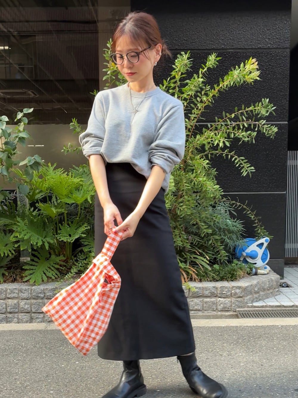 グレー系のスウェット、オレンジ系のエコバッグ/サブバッグ、ブラック系のスカートを着用したレディースの秋コーディネートの4枚目の写真