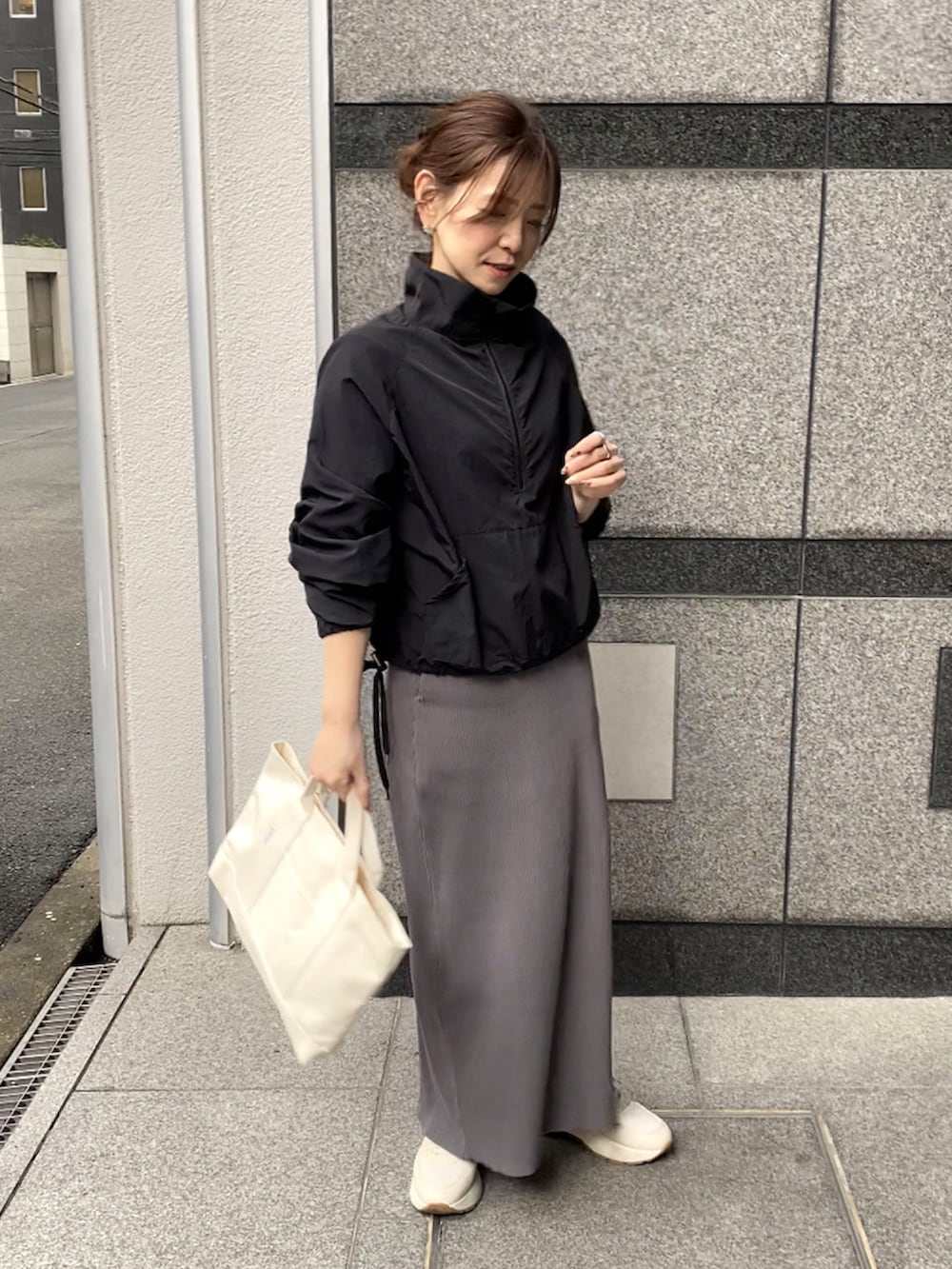 ブラック系のナイロンジャケット、グレー系のスカート、ホワイト系のトートバッグを着用したレディースの春コーディネートの3枚目の写真