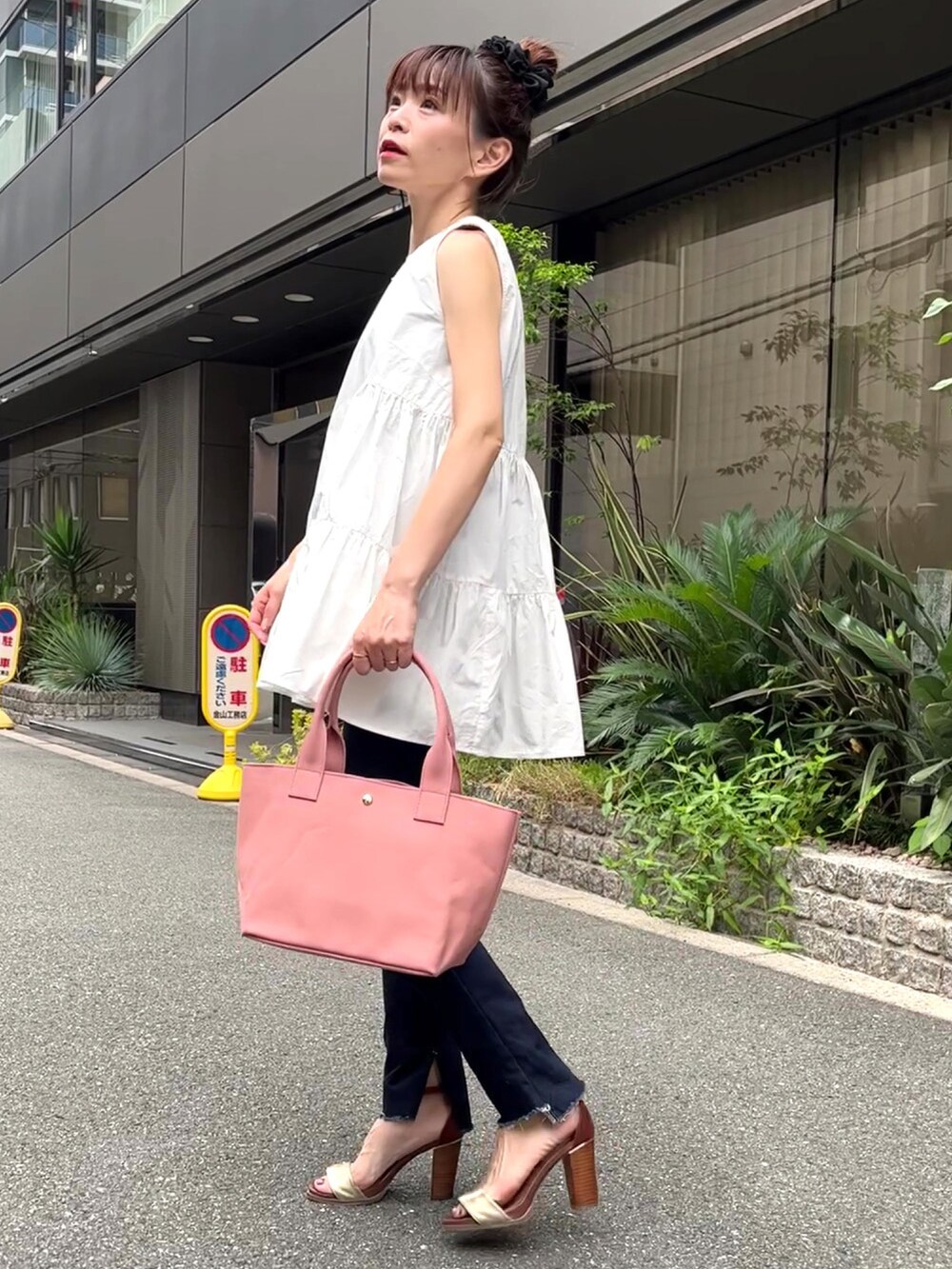 ピンク系のトートバッグ、ホワイト系のシャツ/ブラウス、ブルー系のデニムパンツを着用したレディースの夏コーディネートの3枚目の写真