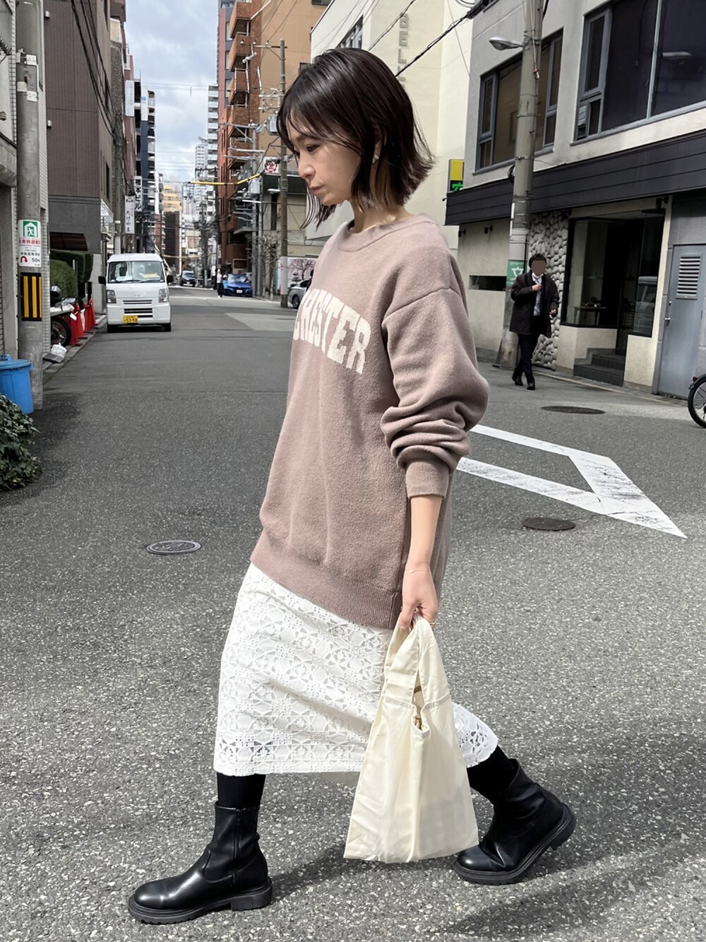 ベージュ系のニット/セーター、ベージュ系のエコバッグ/サブバッグ、ホワイト系のスカートを着用したレディースの春コーディネートの4枚目の写真
