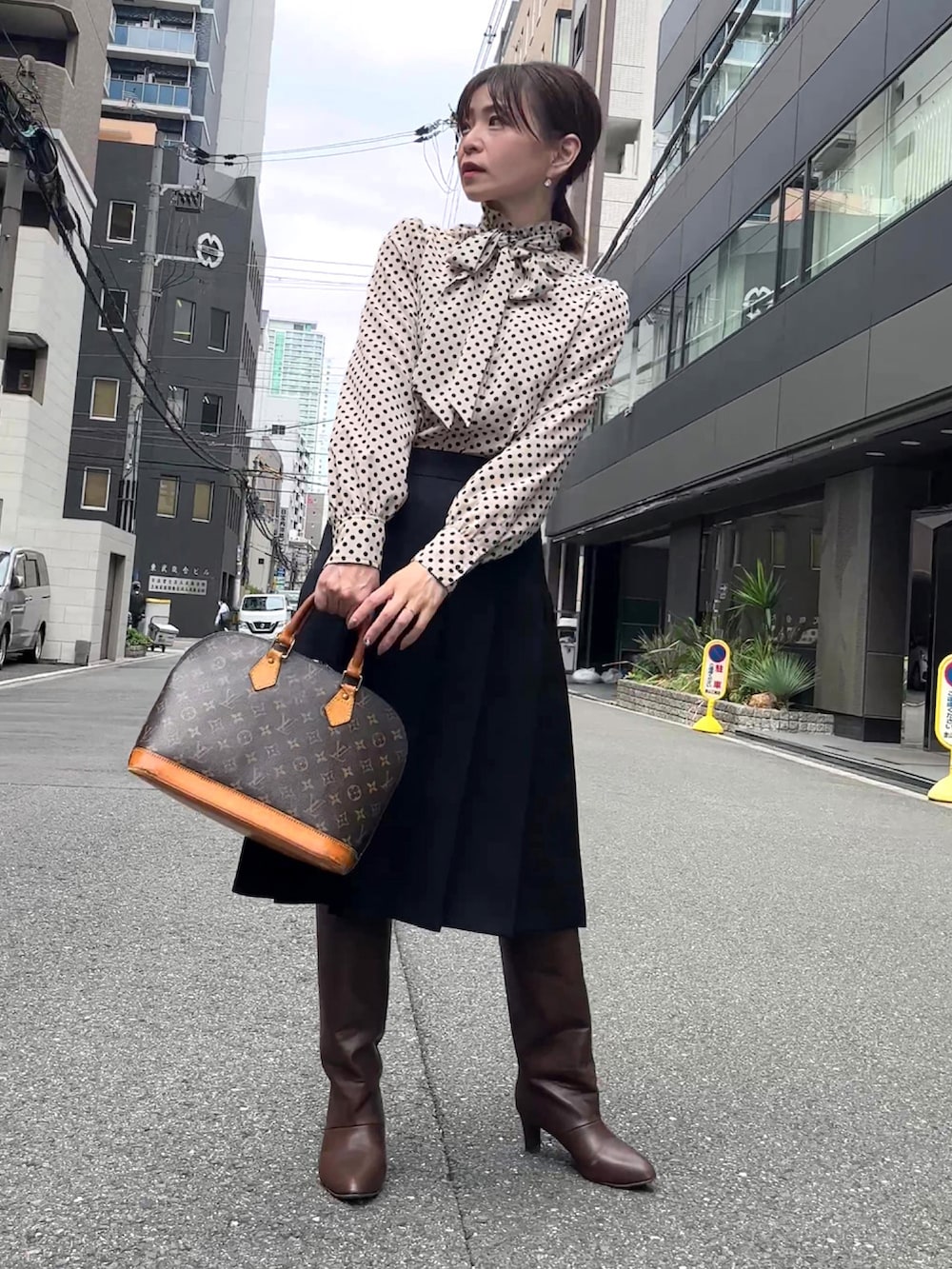 ベージュ系のシャツ/ブラウス、ブラック系のスカート、ブラウン系のハンドバッグを着用したレディースの秋コーディネートの3枚目の写真