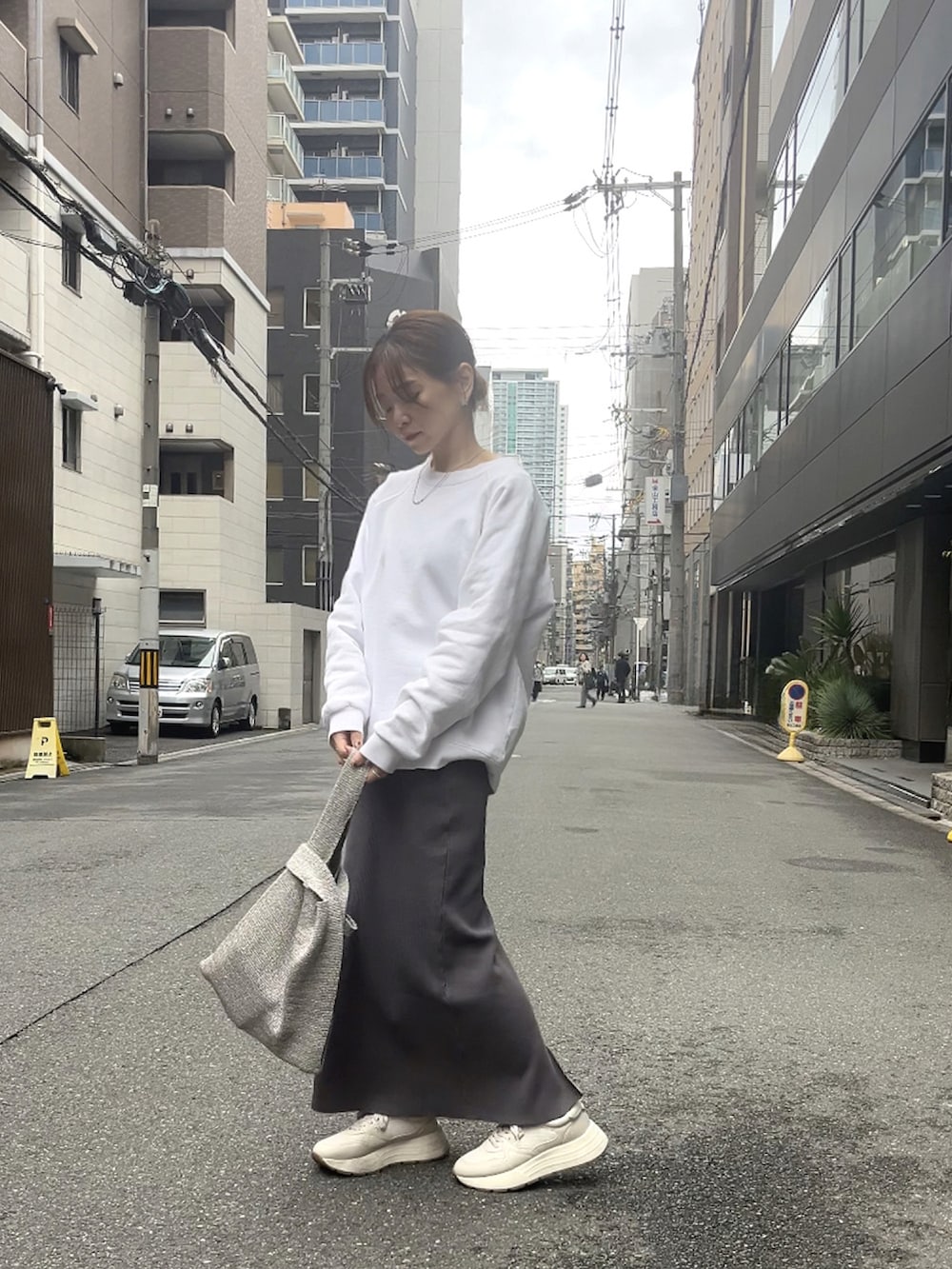 シルバー系のハンドバッグ、グレー系のスカート、ホワイト系のスニーカーを着用したレディースの春コーディネートの4枚目の写真