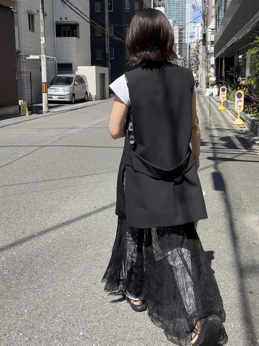 ブラック系のワンピース、ブラック系のサンダル、ブラック系のベストを着用したレディースの夏コーディネートの2枚目の写真