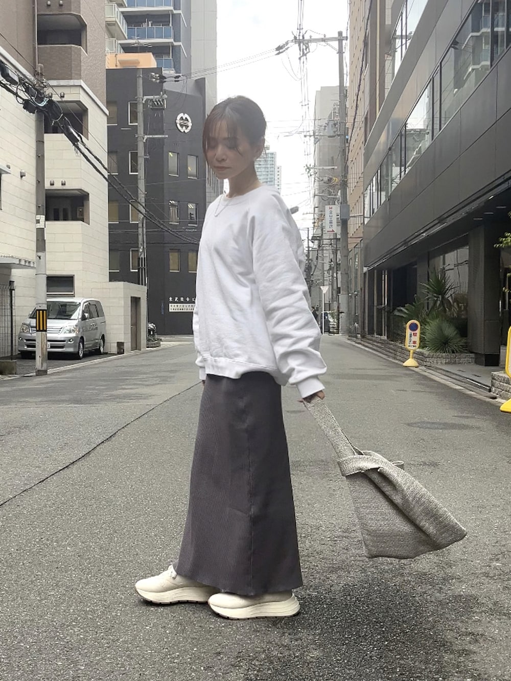 シルバー系のハンドバッグ、グレー系のスカート、ホワイト系のスニーカーを着用したレディースの春コーディネートの2枚目の写真