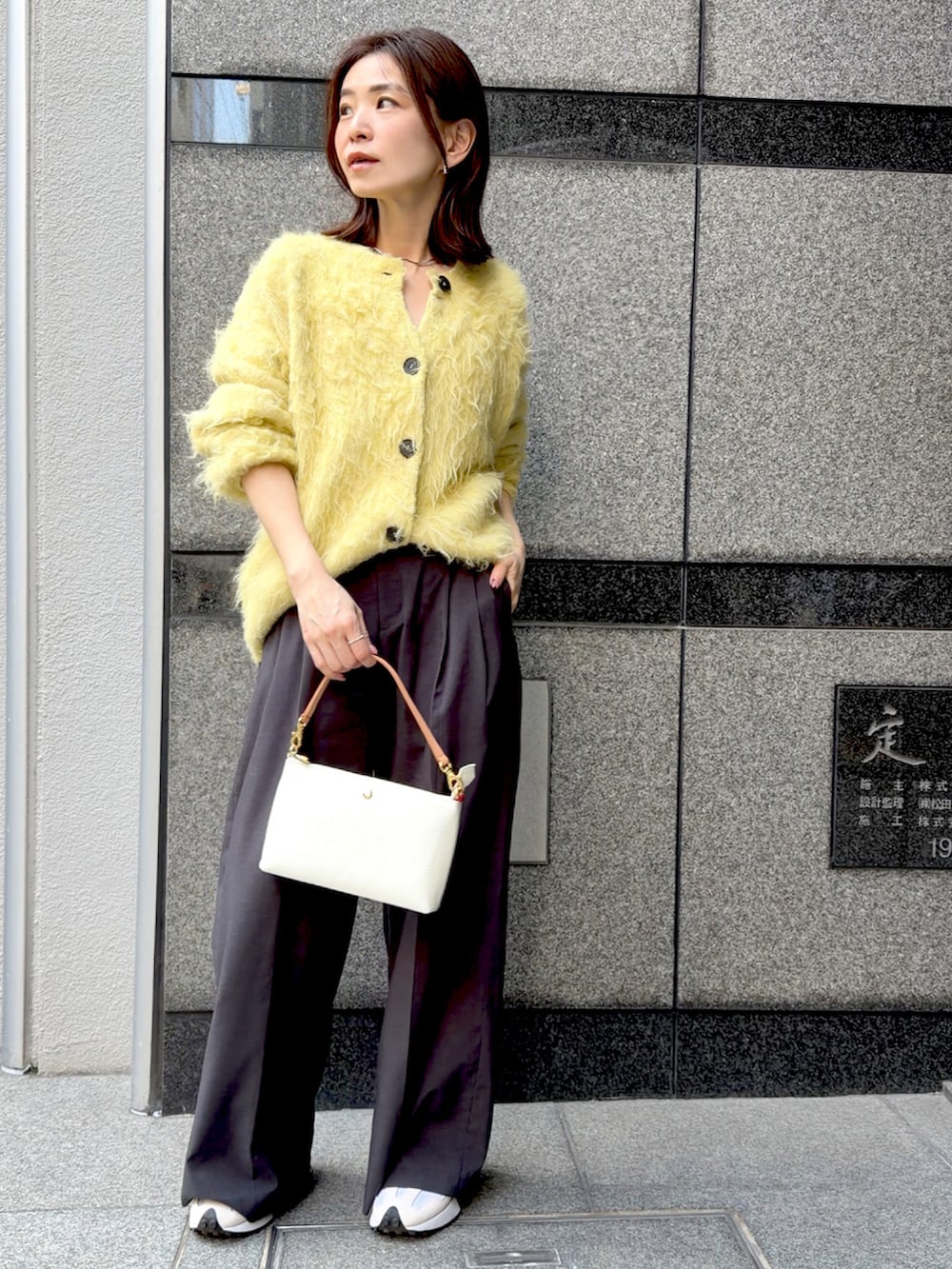 イエロー系のカーディガン/ボレロ、レッド系のハンドバッグ、グレー系のスラックスを着用したレディースの冬コーディネートの2枚目の写真