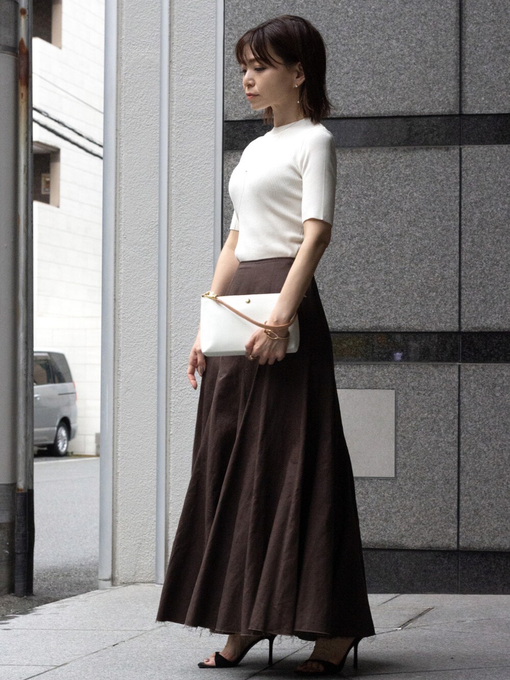 ホワイト系のハンドバッグ、ホワイト系のニット/セーター、ブラウン系のスカートを着用したレディースの夏コーディネートの3枚目の写真