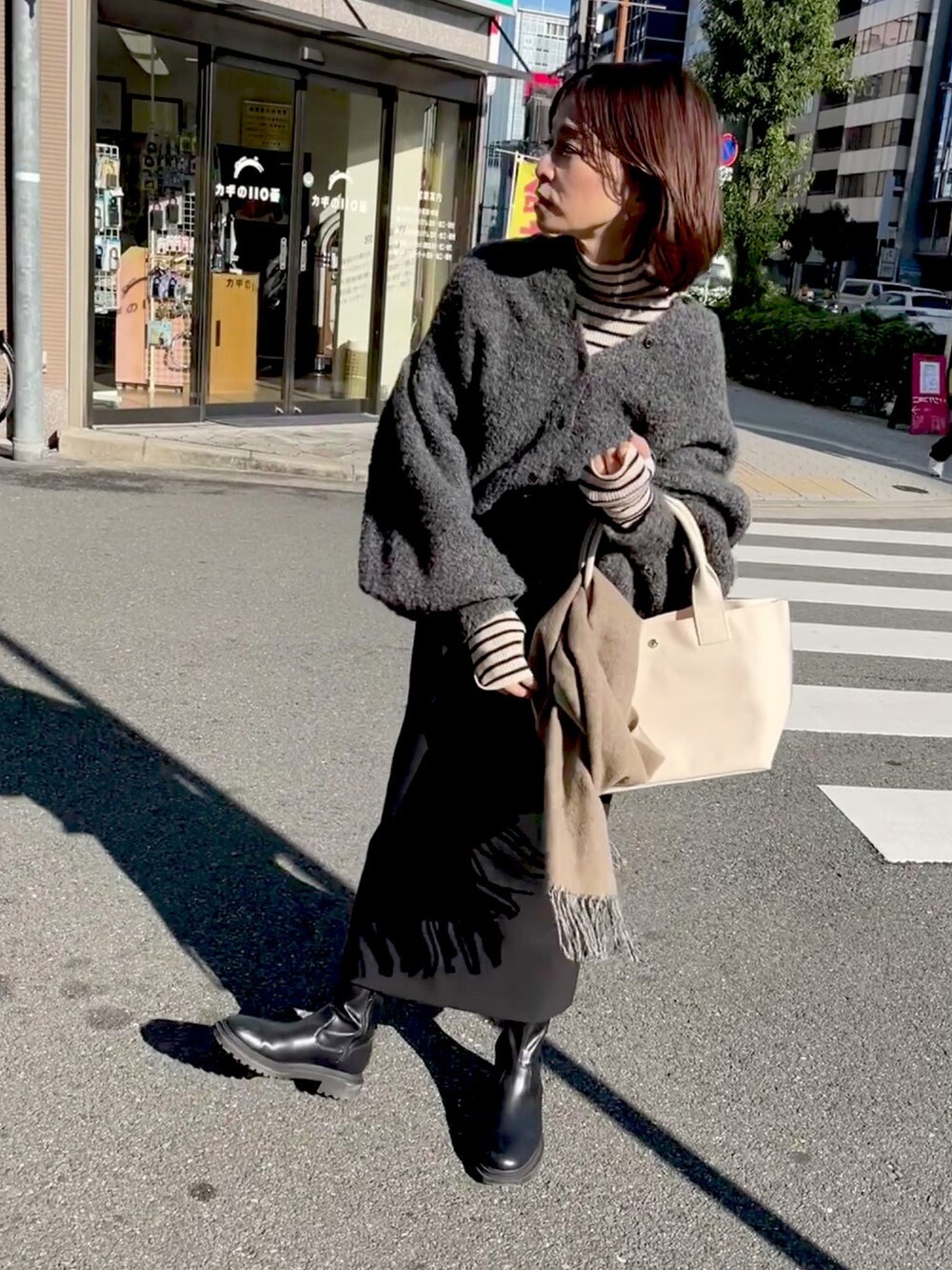 ホワイト系のトートバッグ、グレー系のカーディガン/ボレロ、ブラック系のスカートを着用したレディースの秋コーディネートの4枚目の写真