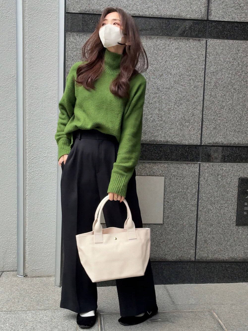 ホワイト系のトートバッグ、グリーン系のニット/セーター、ブラック系のスラックスを着用したレディースの冬コーディネートの2枚目の写真