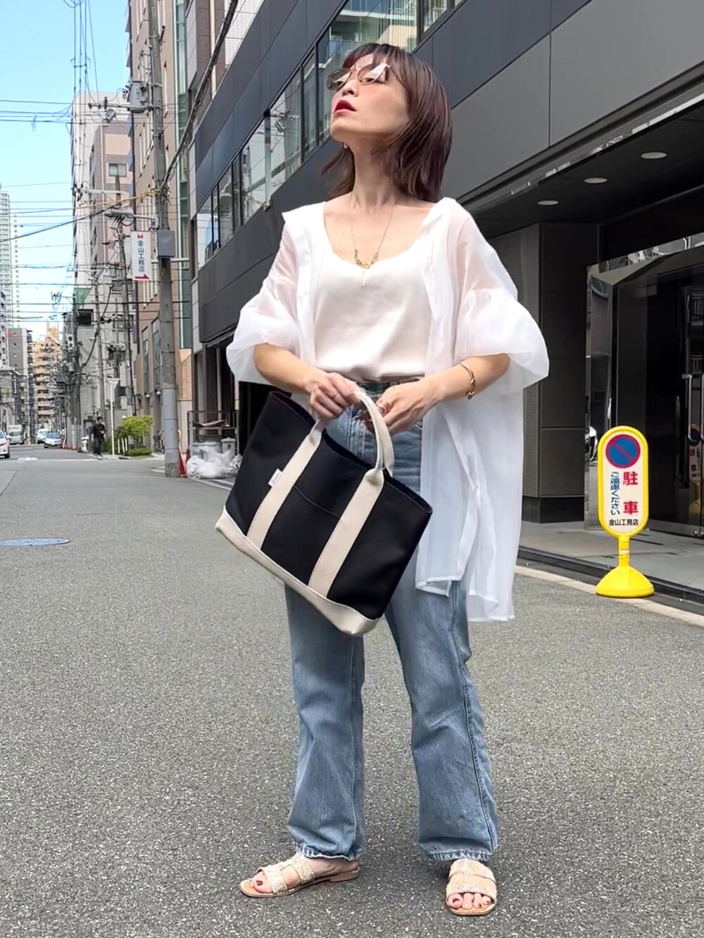 ベージュ系のトートバッグ、ホワイト系のシャツ/ブラウス、ブルー系のデニムパンツを着用したレディースの夏コーディネートの2枚目の写真