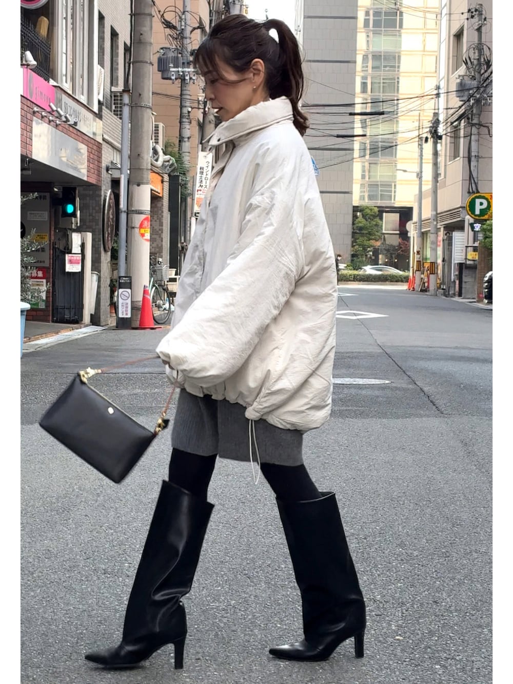 ホワイト系のブルゾン、ブラック系のショルダーバッグ、ブラック系のブーツを着用したレディースの冬コーディネートの2枚目の写真
