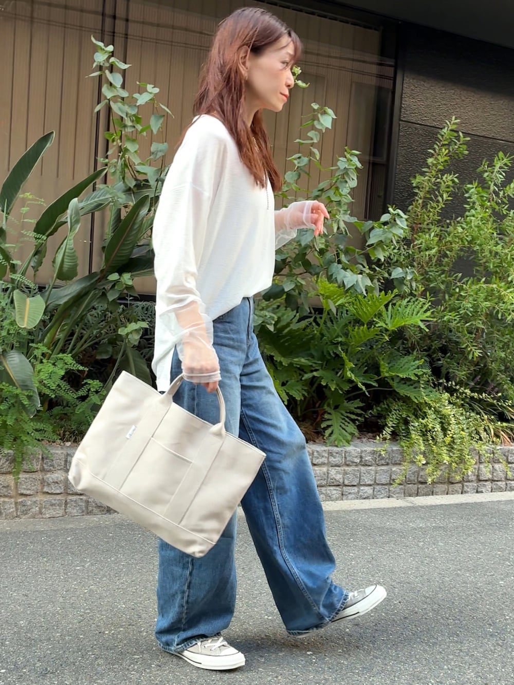 ホワイト系のTシャツ/カットソー、ホワイト系のトートバッグ、ブルー系のデニムパンツを着用したレディースの秋コーディネートの2枚目の写真
