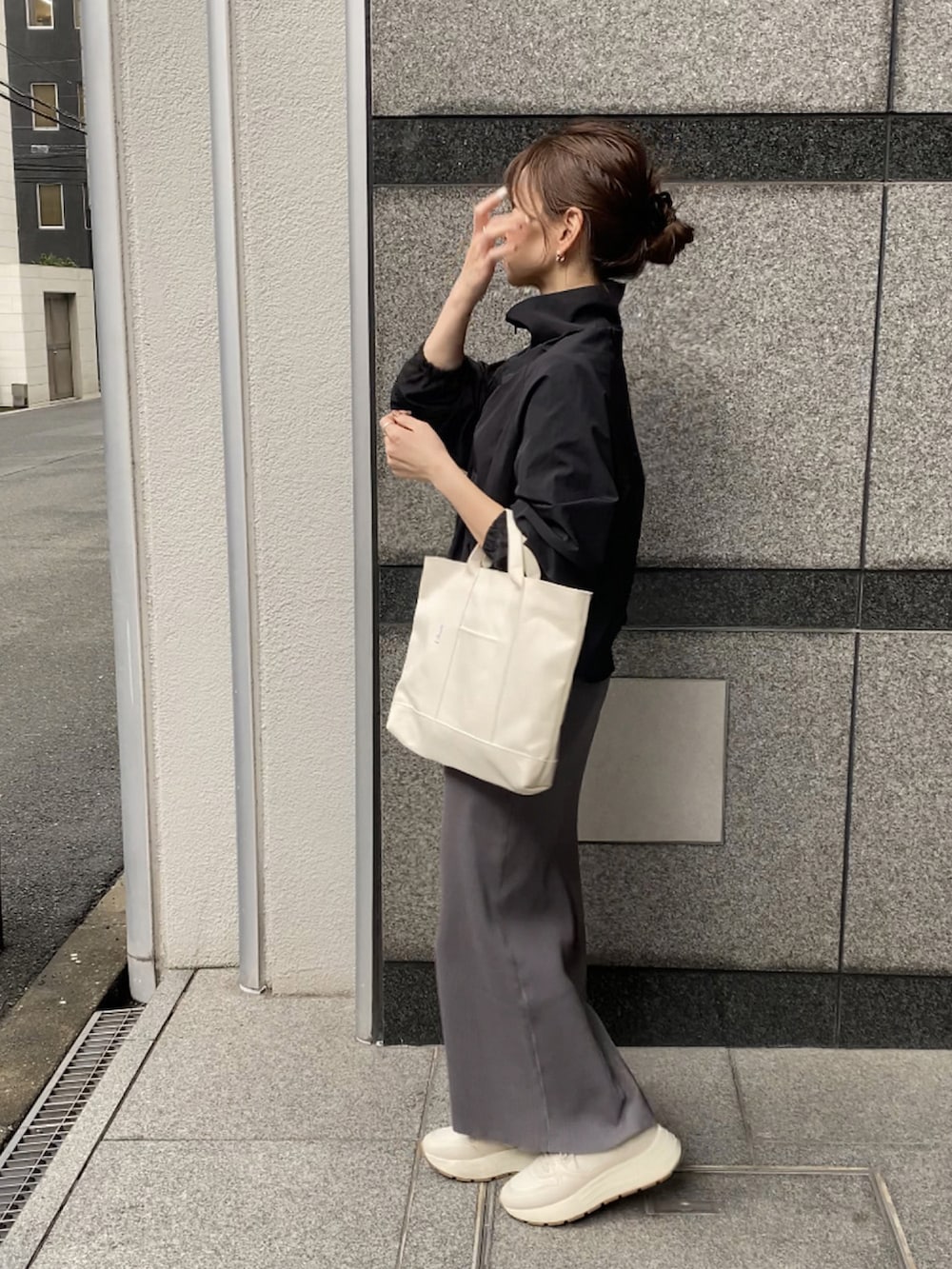 ブラック系のナイロンジャケット、グレー系のスカート、ホワイト系のトートバッグを着用したレディースの春コーディネートの2枚目の写真