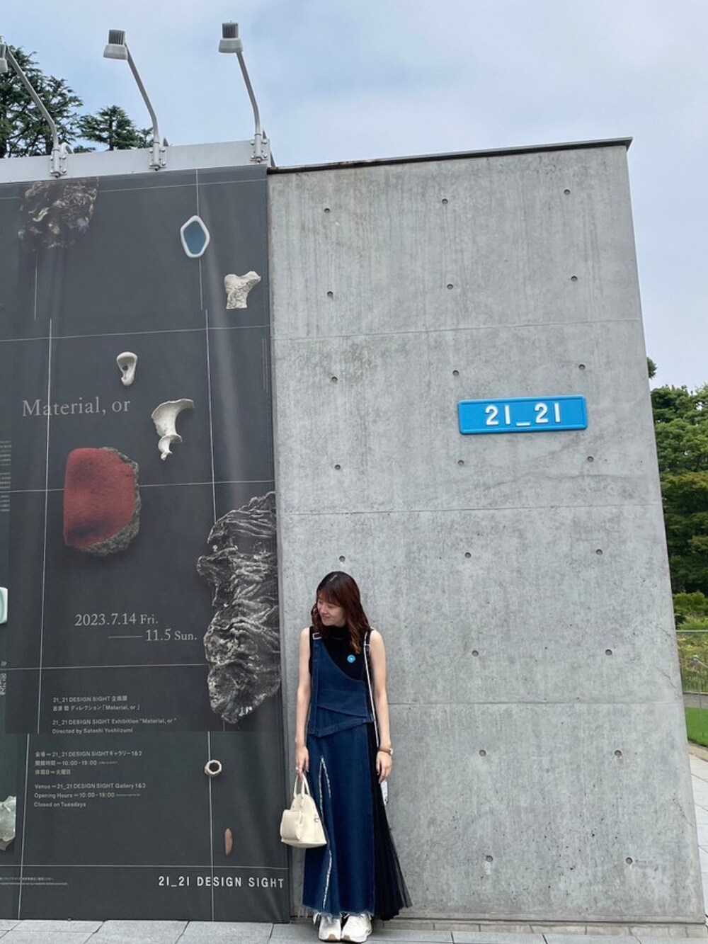 ブルー系のジャンパースカート、ブラック系のトップス、ベージュ系のスニーカーを着用したレディースの秋コーディネートの2枚目の写真