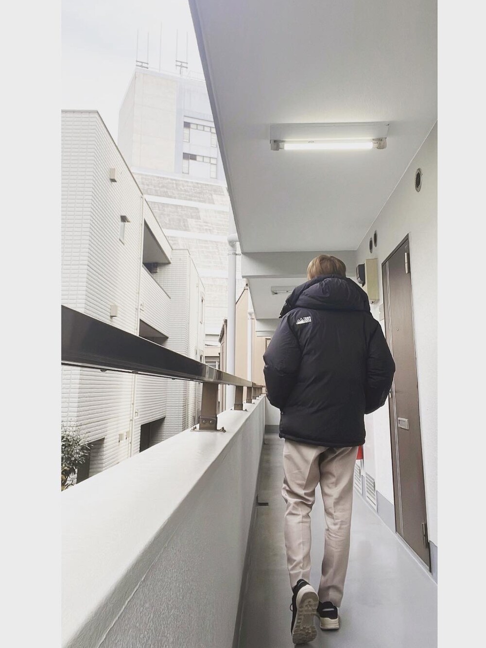 ブラック系のダウンジャケット/コート、ブラック系のTシャツ/カットソー、ベージュ系のスラックスを着用したメンズの冬コーディネートの3枚目の写真