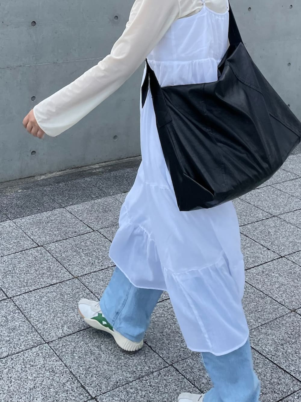 ベージュ系のスニーカー、ブルー系のデニムパンツ、ホワイト系のワンピースを着用したレディースの夏コーディネートの2枚目の写真