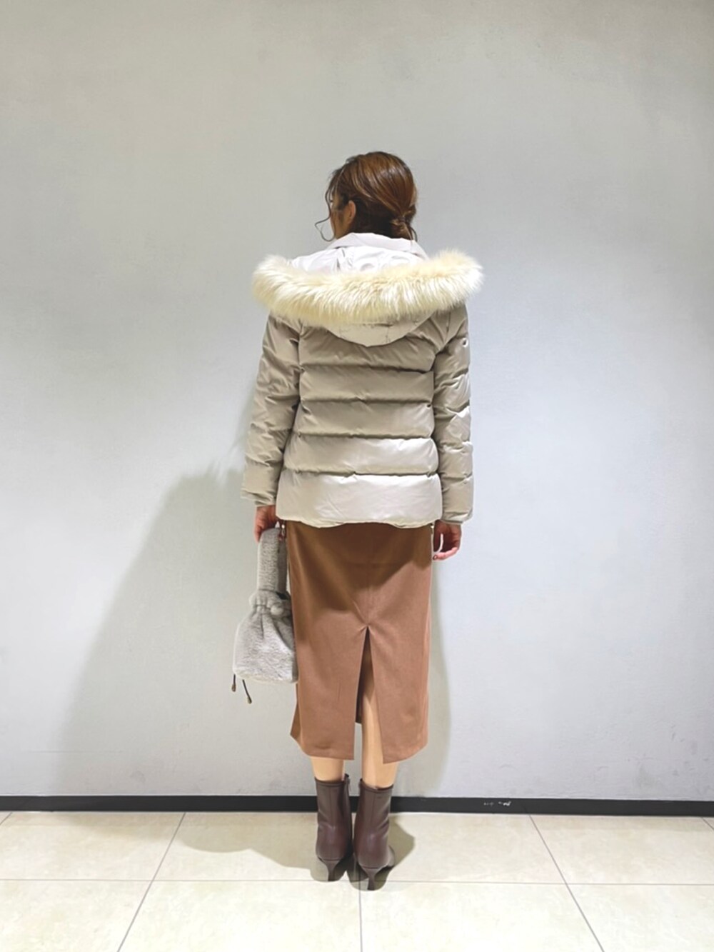 ブラック系のニット/セーター、ベージュ系のダウンジャケット/コート、ブラウン系のスカートを着用したレディースの秋コーディネートの4枚目の写真