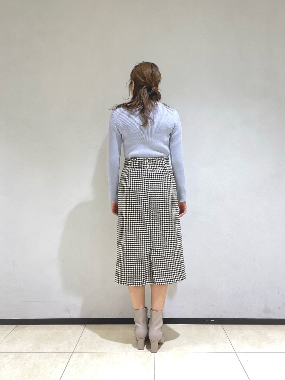 グレー系のニット/セーター、ホワイト系のスカート、ベージュ系のブーツを着用したレディースの冬コーディネートの3枚目の写真