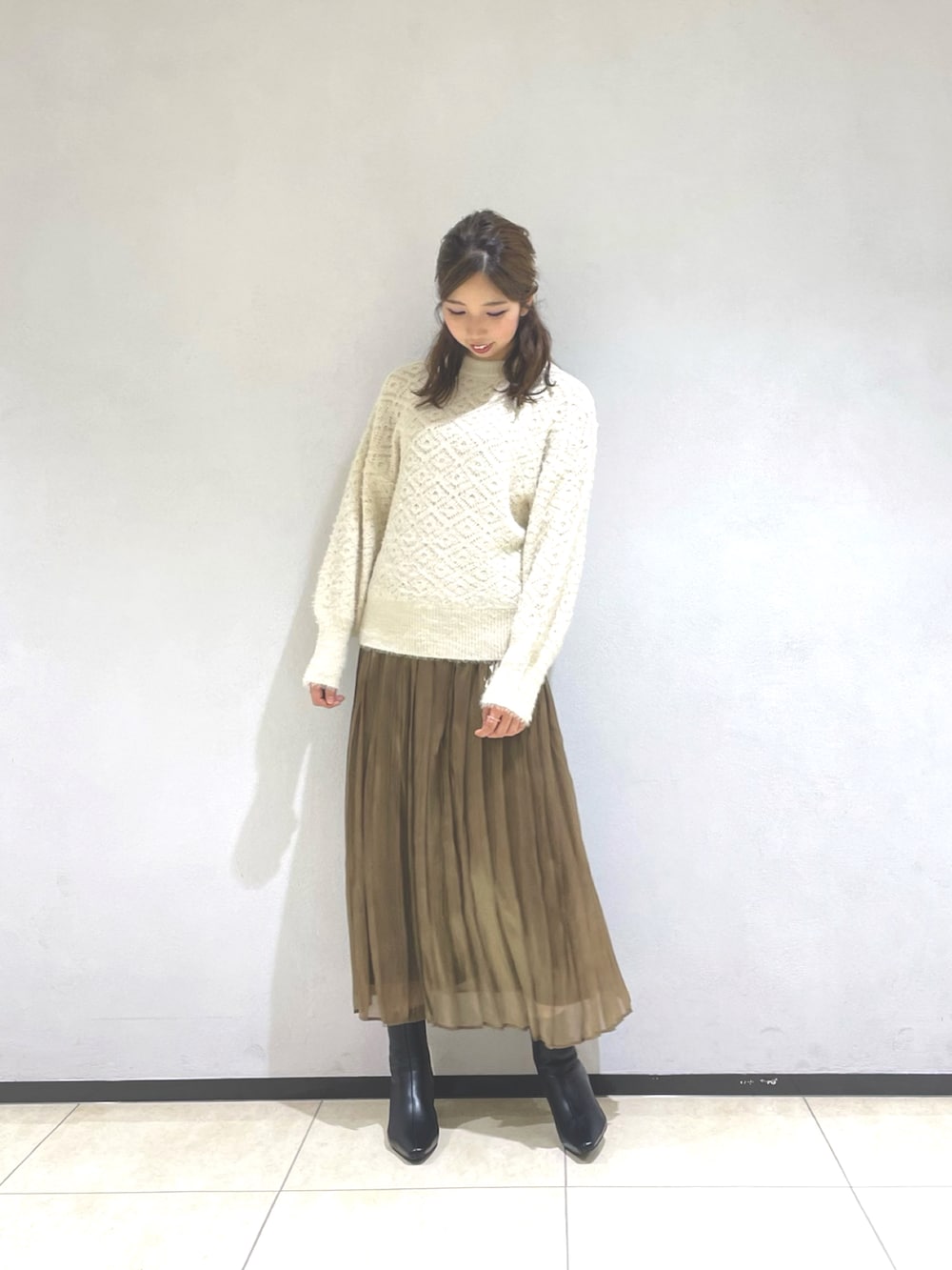 ベージュ系のノーカラーコート、ホワイト系のニット/セーター、グレー系のスカートを着用したレディースの秋コーディネートの3枚目の写真