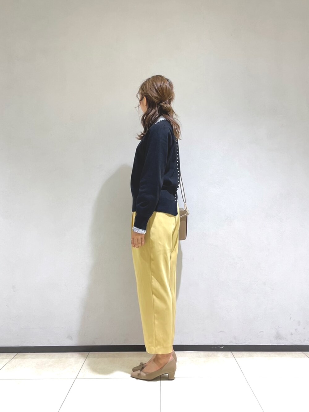 ブラック系のニット/セーター、ブルー系のシャツ/ブラウス、イエロー系のショルダーバッグを着用したレディースの秋コーディネートの2枚目の写真