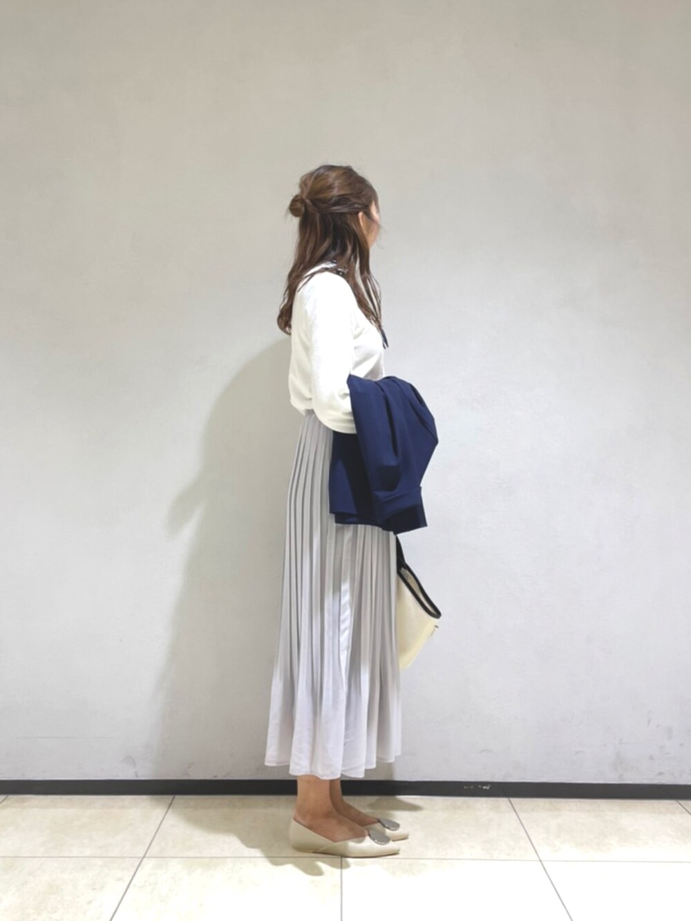 ホワイト系のニット/セーター、ブルー系のジャケット/アウター、グレー系のスカートを着用したレディースの春コーディネートの3枚目の写真