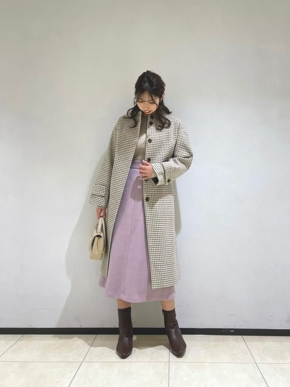 ベージュ系のニット/セーター、ピンク系のスカート、ベージュ系のショルダーバッグを着用したレディースの冬コーディネートの2枚目の写真