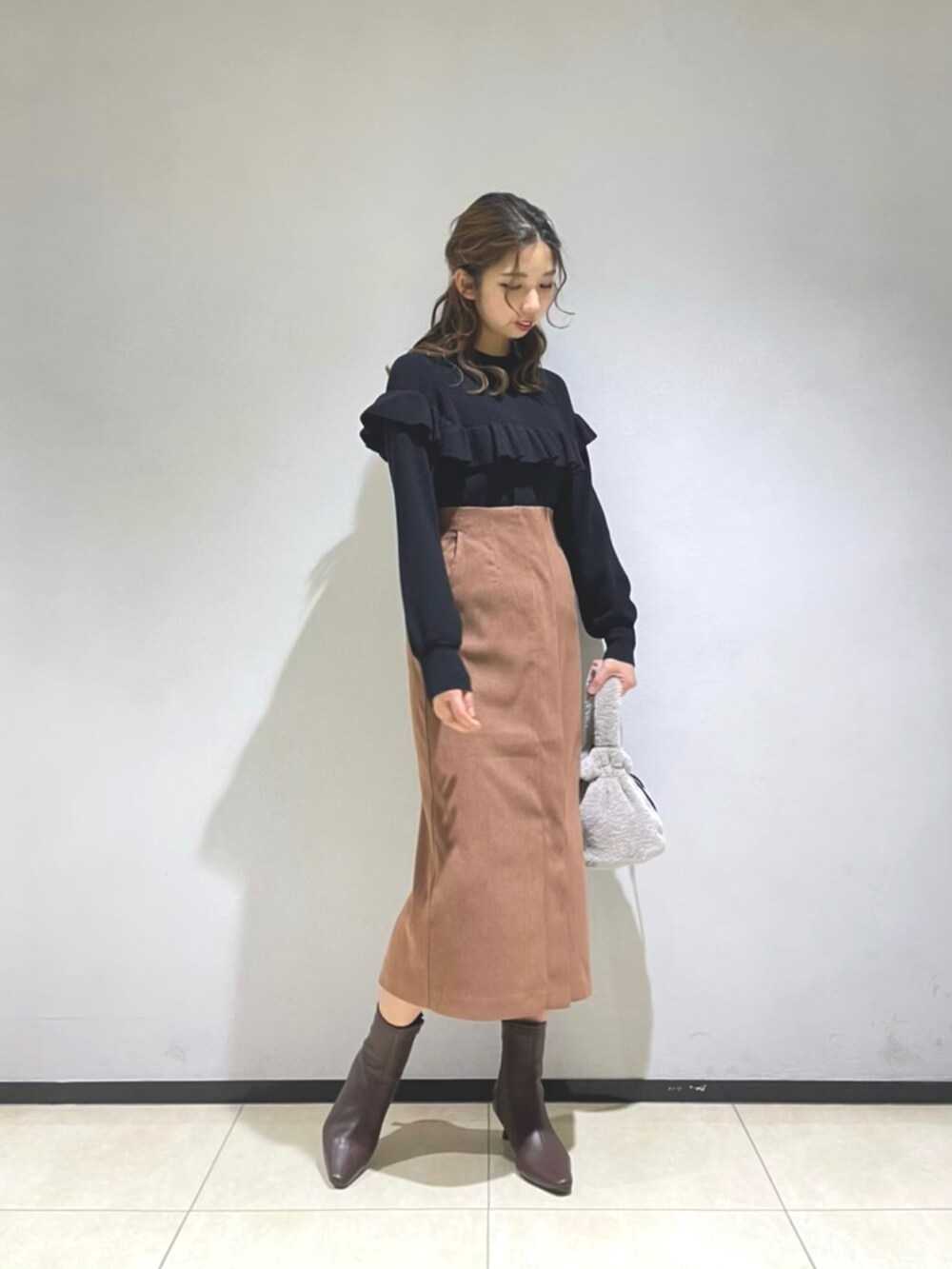ブラック系のニット/セーター、ベージュ系のダウンジャケット/コート、ブラウン系のスカートを着用したレディースの秋コーディネートの2枚目の写真