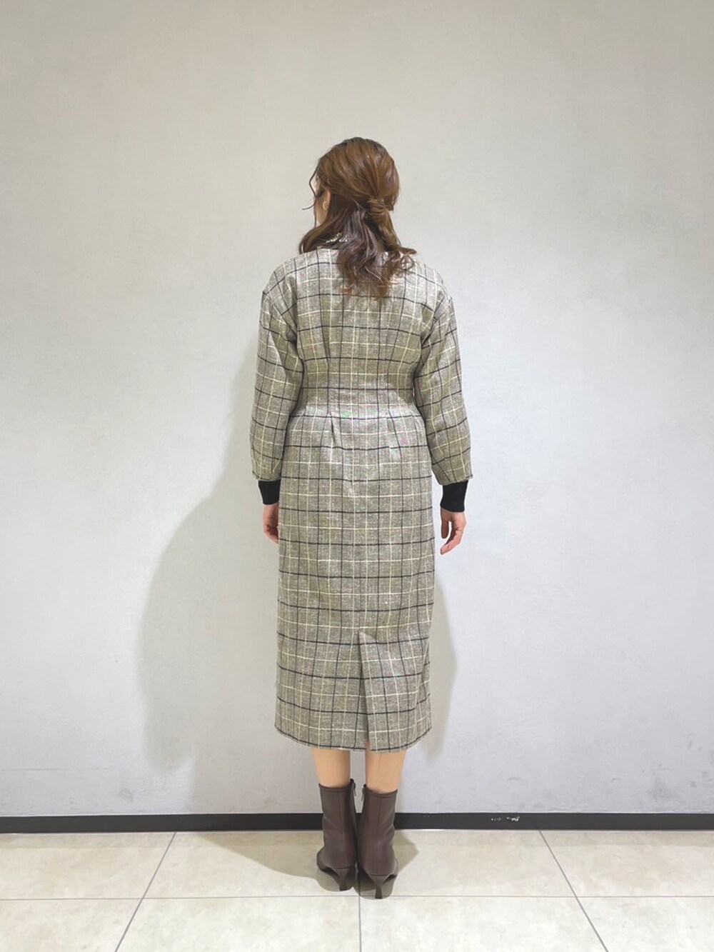 ブラック系のニット/セーター、ブラウン系のブーツ、グレー系のワンピースを着用したレディースの冬コーディネートの3枚目の写真