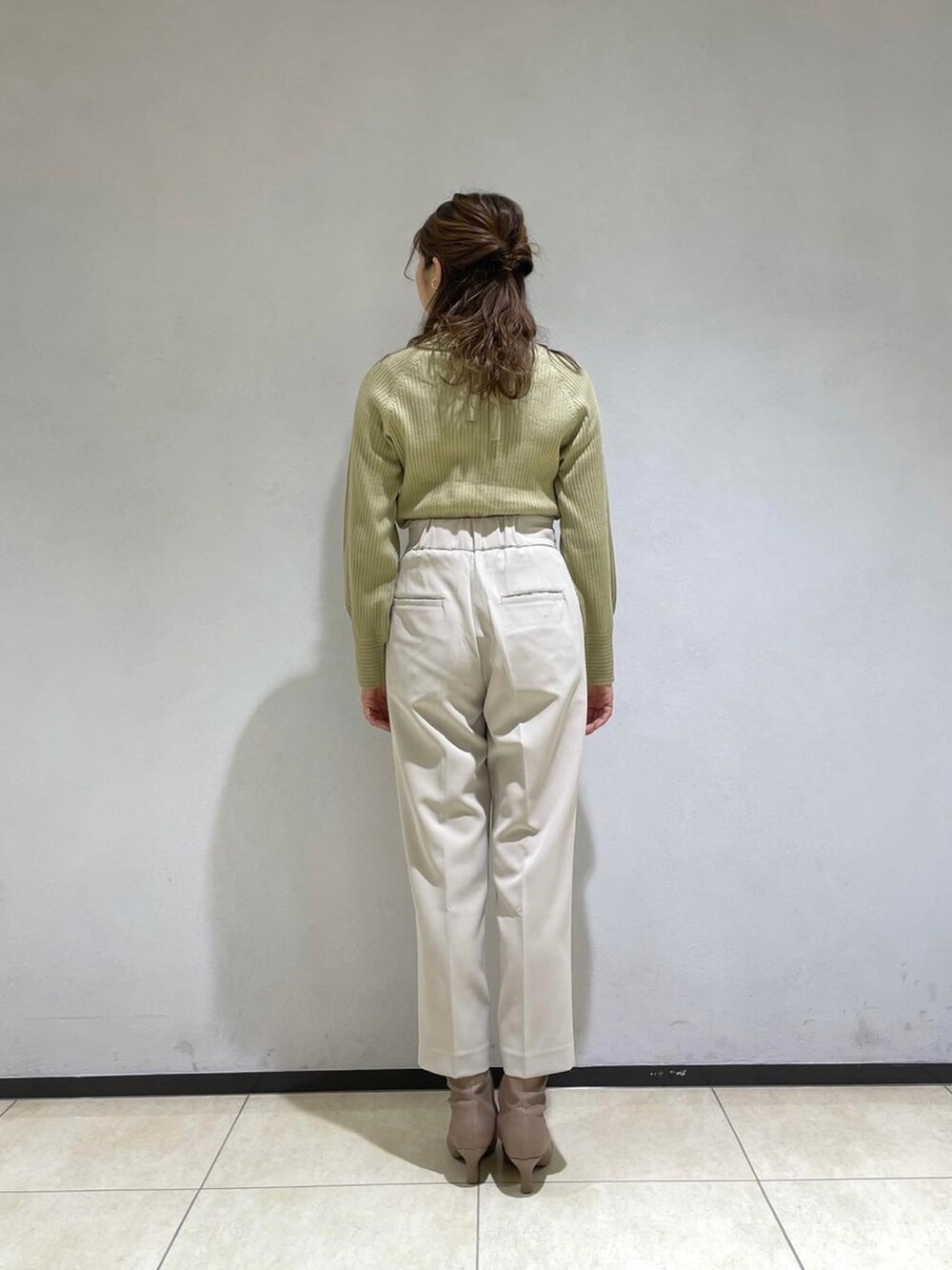 ブラック系のノーカラーコート、ベージュ系のその他パンツ、グリーン系のニット/セーターを着用したレディースの冬コーディネートの4枚目の写真