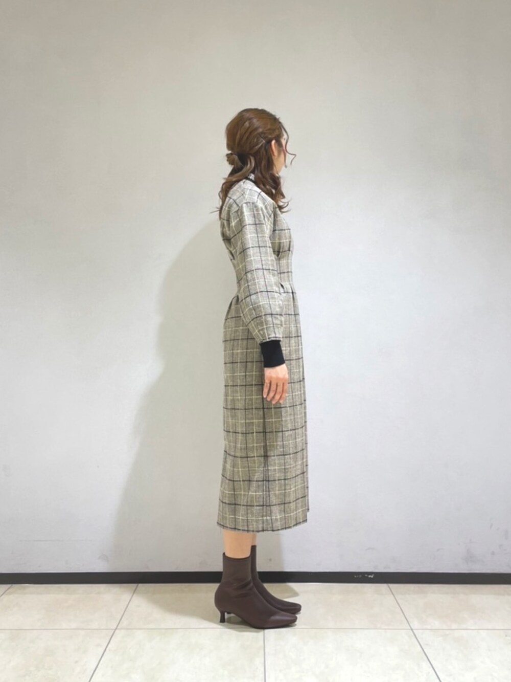 ブラック系のニット/セーター、ブラウン系のブーツ、グレー系のワンピースを着用したレディースの冬コーディネートの2枚目の写真