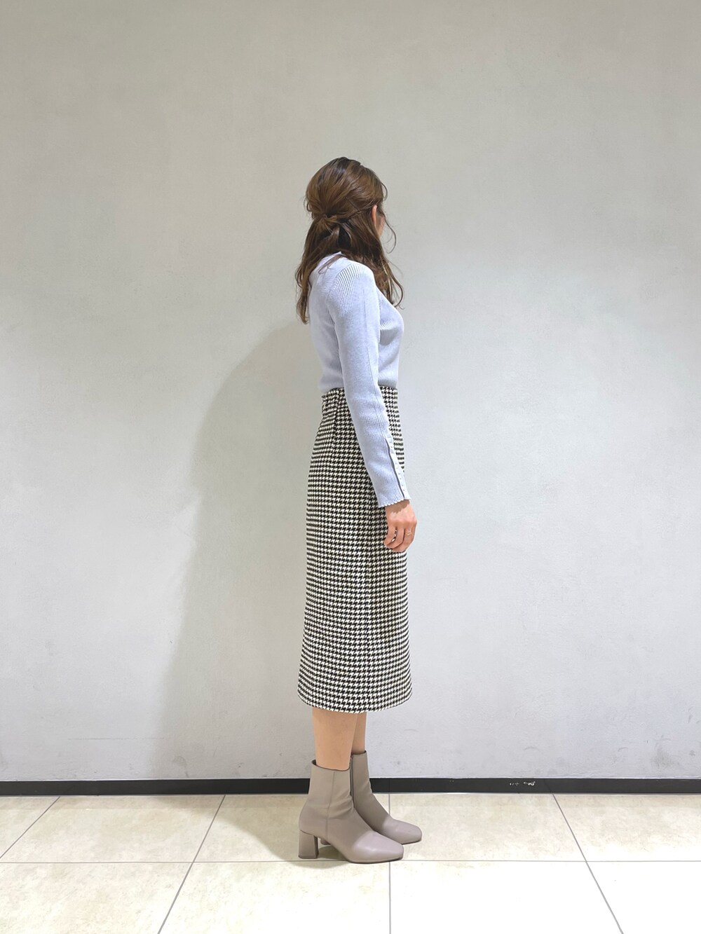 グレー系のニット/セーター、ホワイト系のスカート、ベージュ系のブーツを着用したレディースの冬コーディネートの2枚目の写真