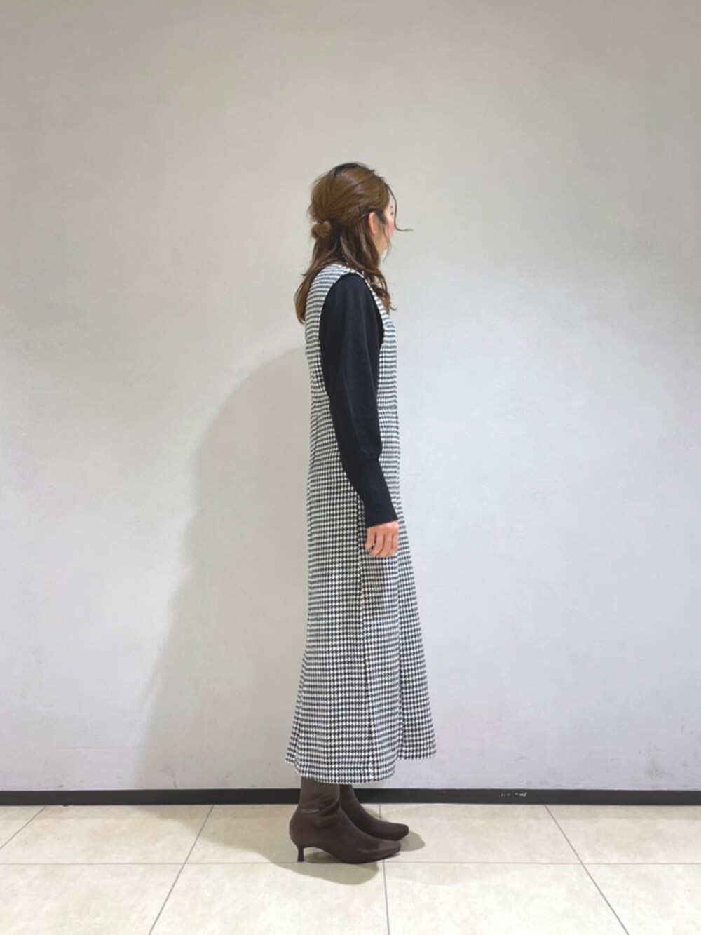 ホワイト系のジャンパースカート、ブラック系のニット/セーター、ベージュ系のショルダーバッグを着用したレディースの冬コーディネートの2枚目の写真