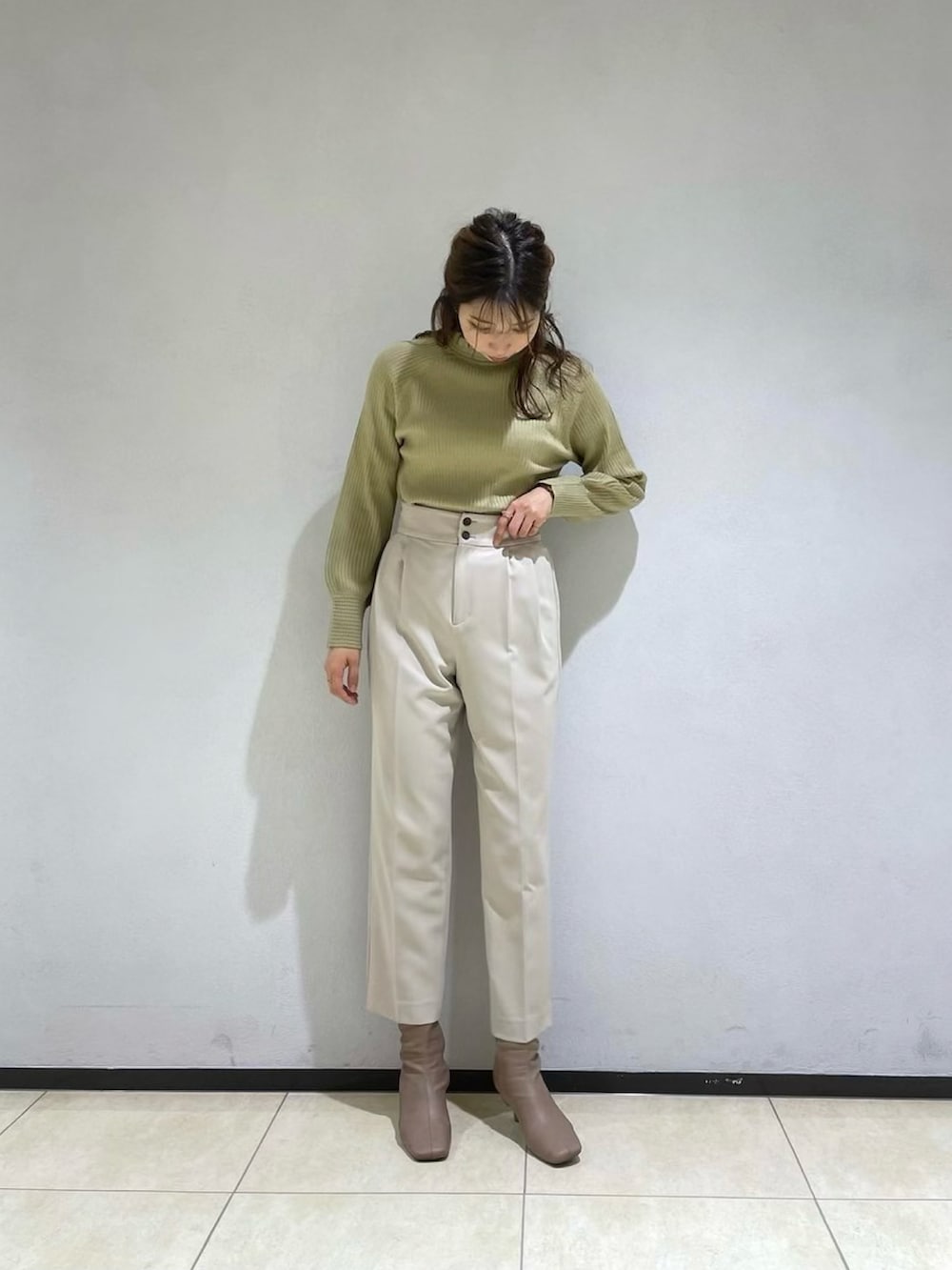 ブラック系のノーカラーコート、ベージュ系のその他パンツ、グリーン系のニット/セーターを着用したレディースの冬コーディネートの2枚目の写真