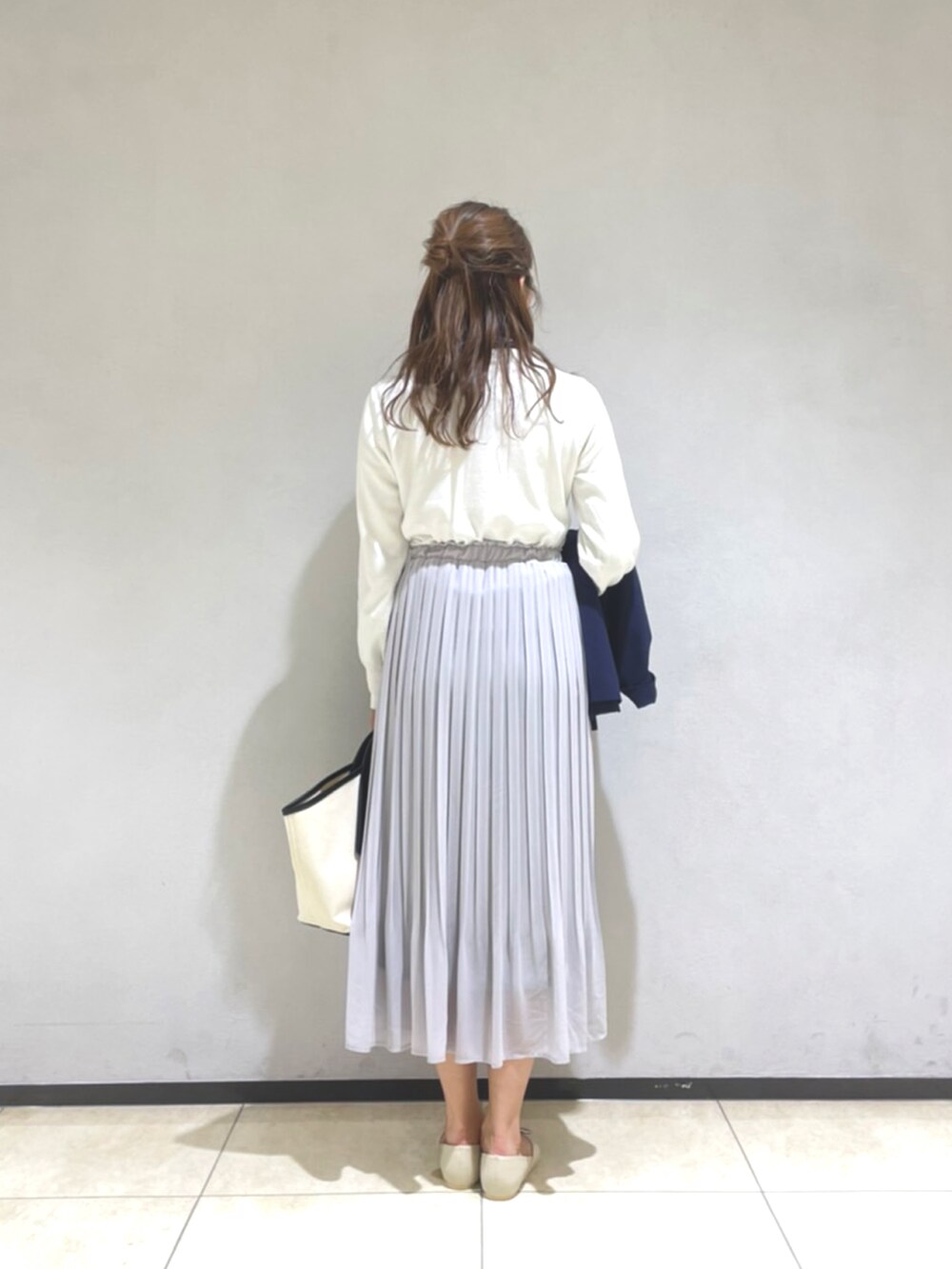 ホワイト系のニット/セーター、ブルー系のジャケット/アウター、グレー系のスカートを着用したレディースの春コーディネートの4枚目の写真