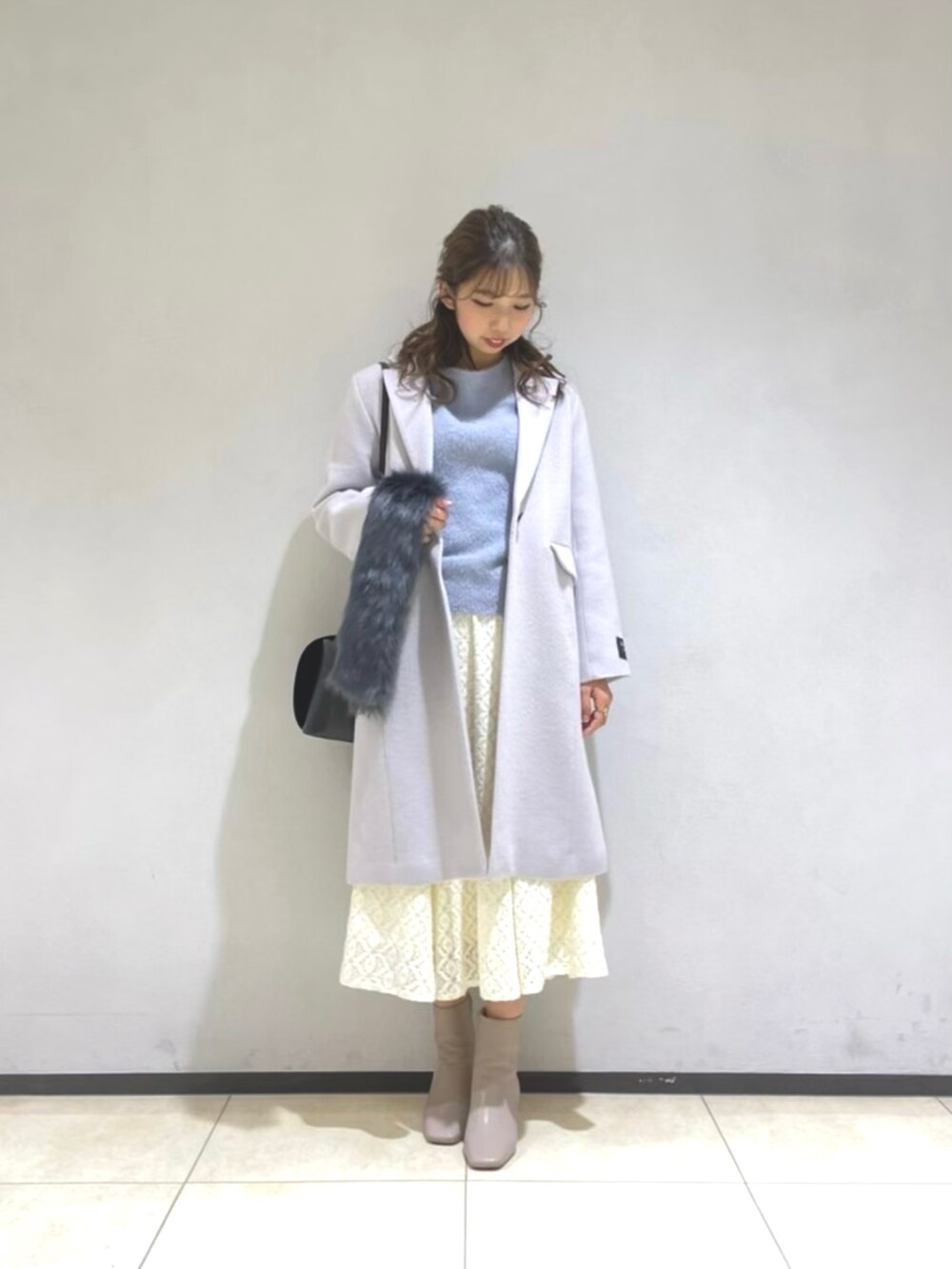 ホワイト系のスカート、ブルー系のニット/セーター、ブラック系のショルダーバッグを着用したレディースの冬コーディネートの2枚目の写真